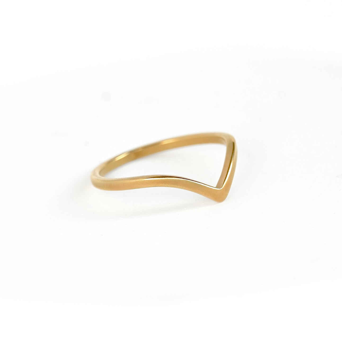 A minimalist gold ring with a wavy, open triangular design, photographed on a clean white background.