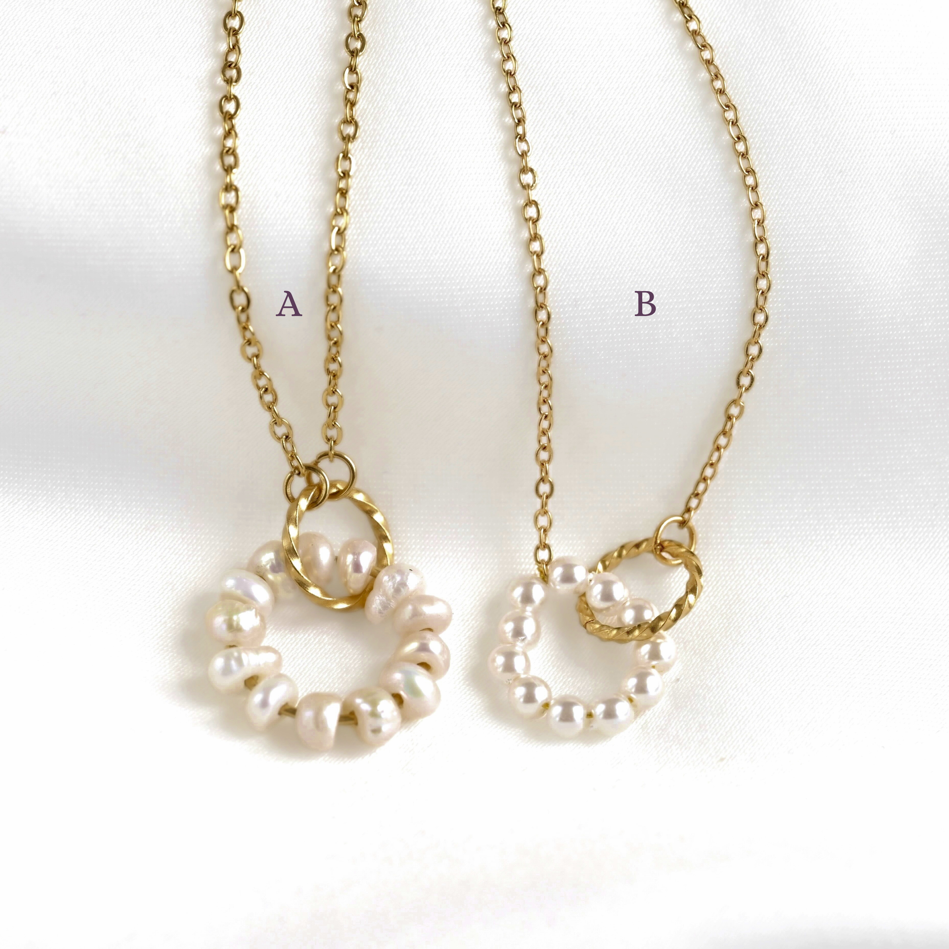 Two gold chain necklaces with circular pearl pendants labeled A and B, displayed on a white fabric background.