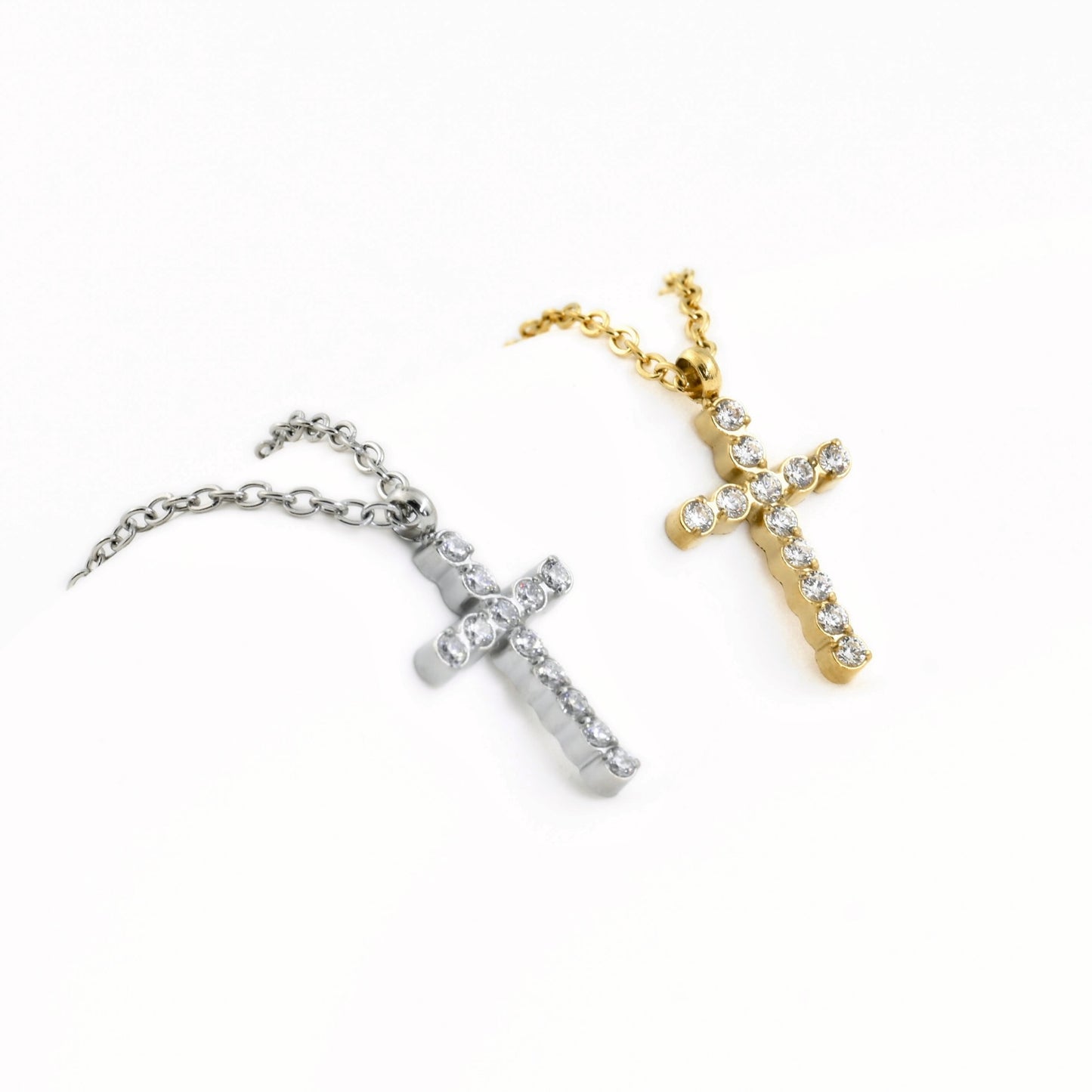 Two cross necklaces, one silver and one gold, on a white background