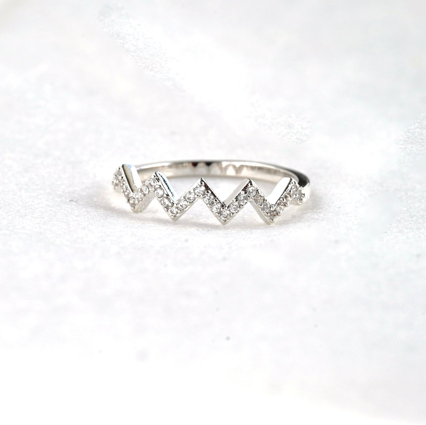 Silver ring with a chevron design on a white background