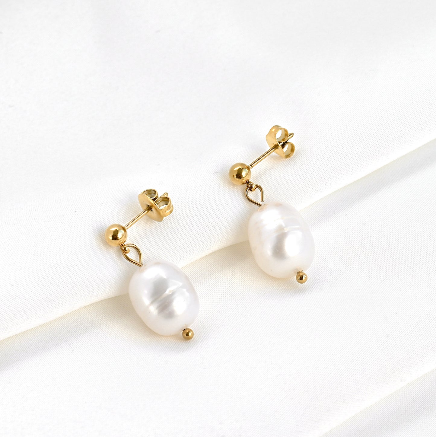 Pearl  dangle earrings with gold ball posts on a white background