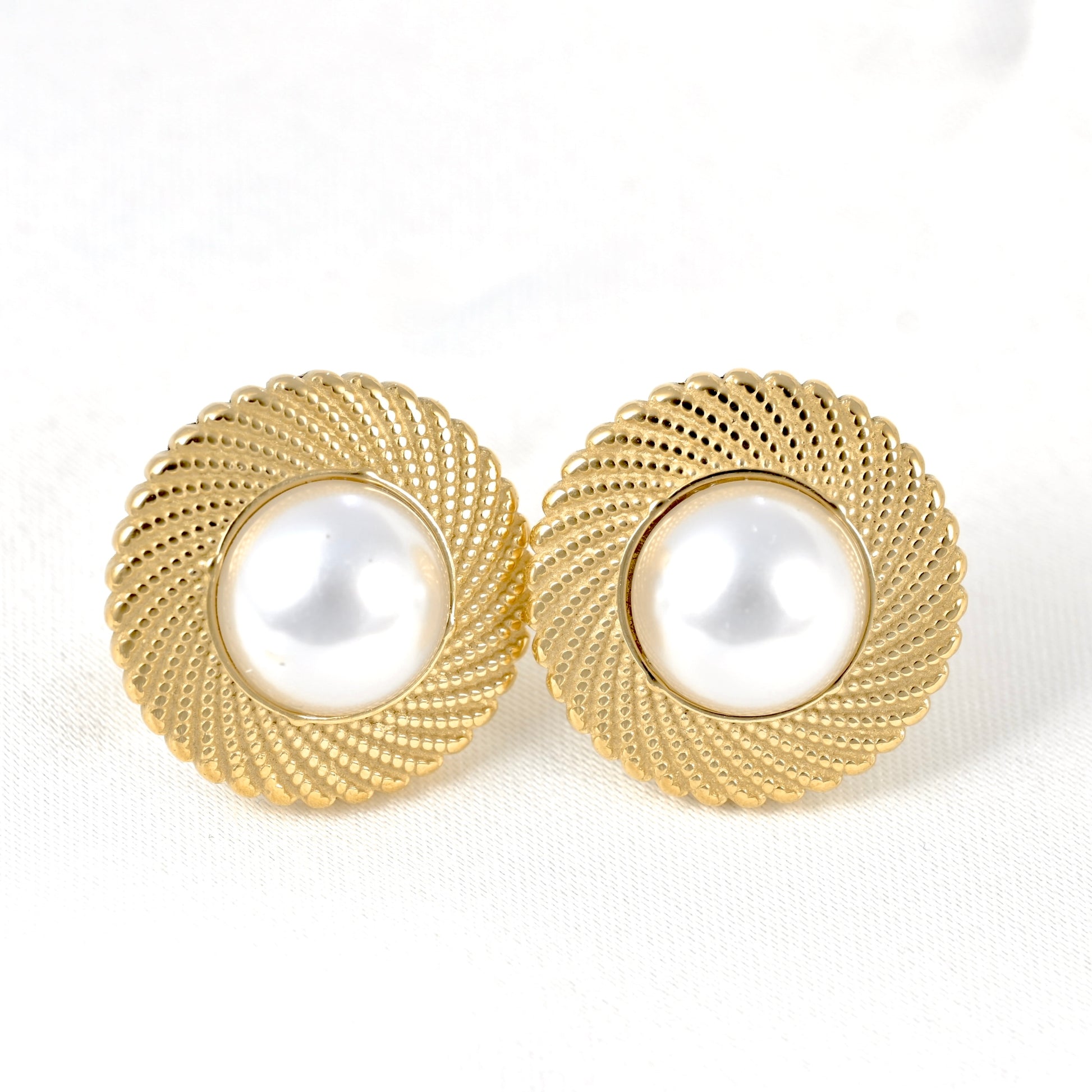 Close up front view of a pair of vintage-style gold pearl earrings on white background