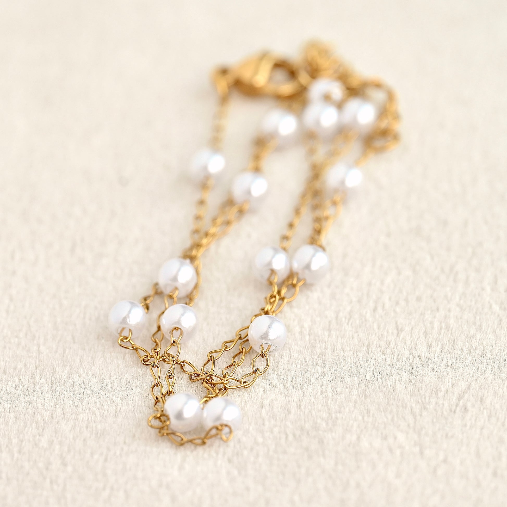 Gold chain necklace with pearls on a beige background