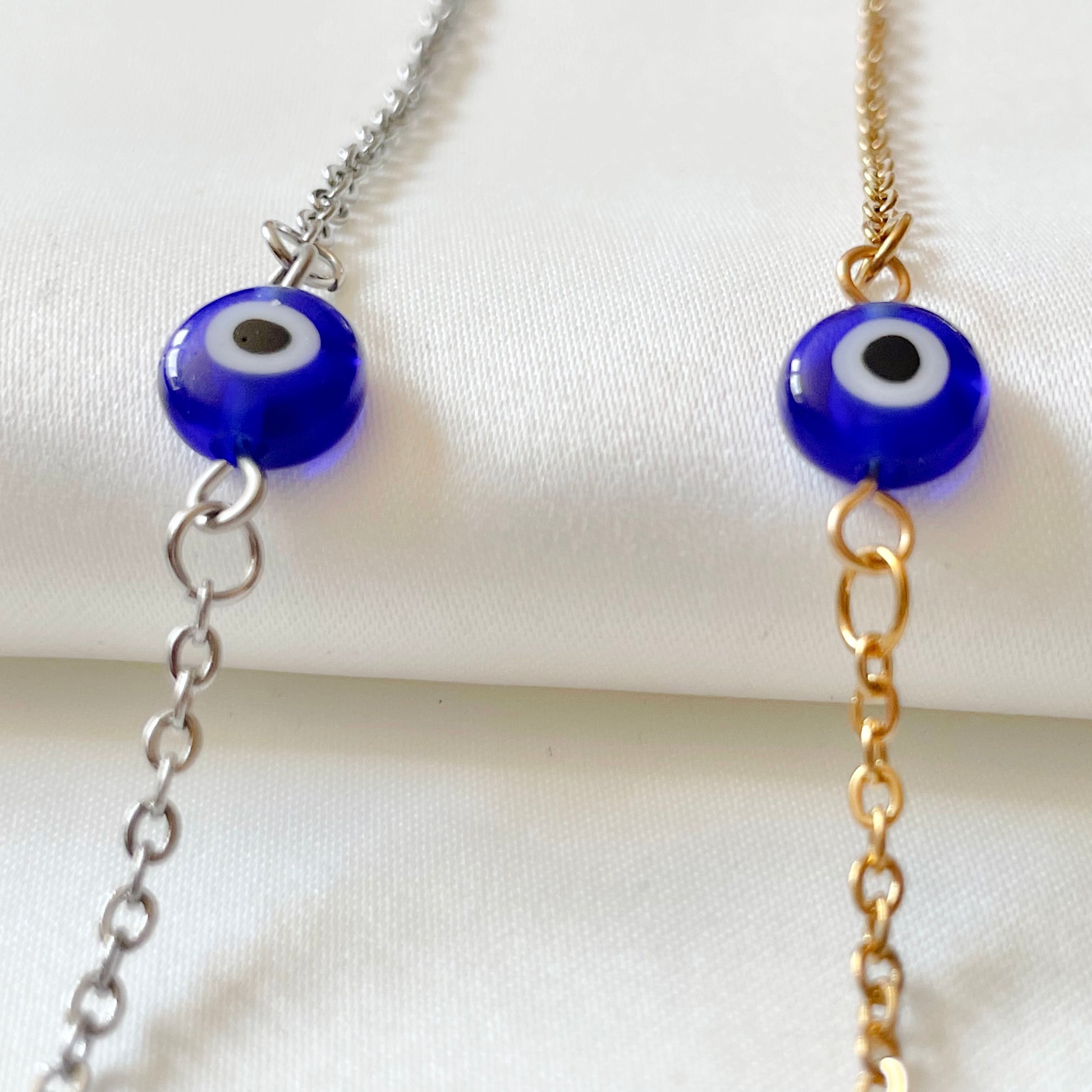 Two blue eye bracelets, one gold one silver, positioned vertically on a white background