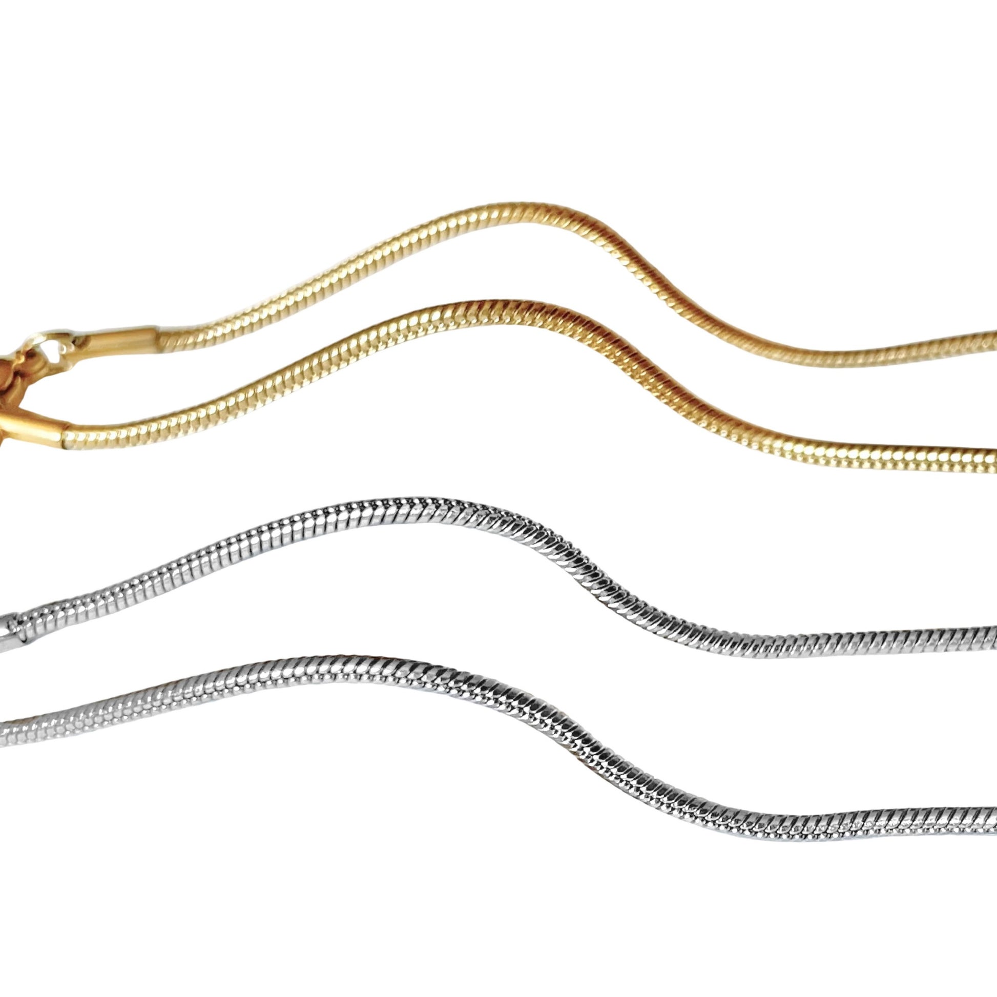 Close-up view of two gold and silver snake chain anklets on a white background