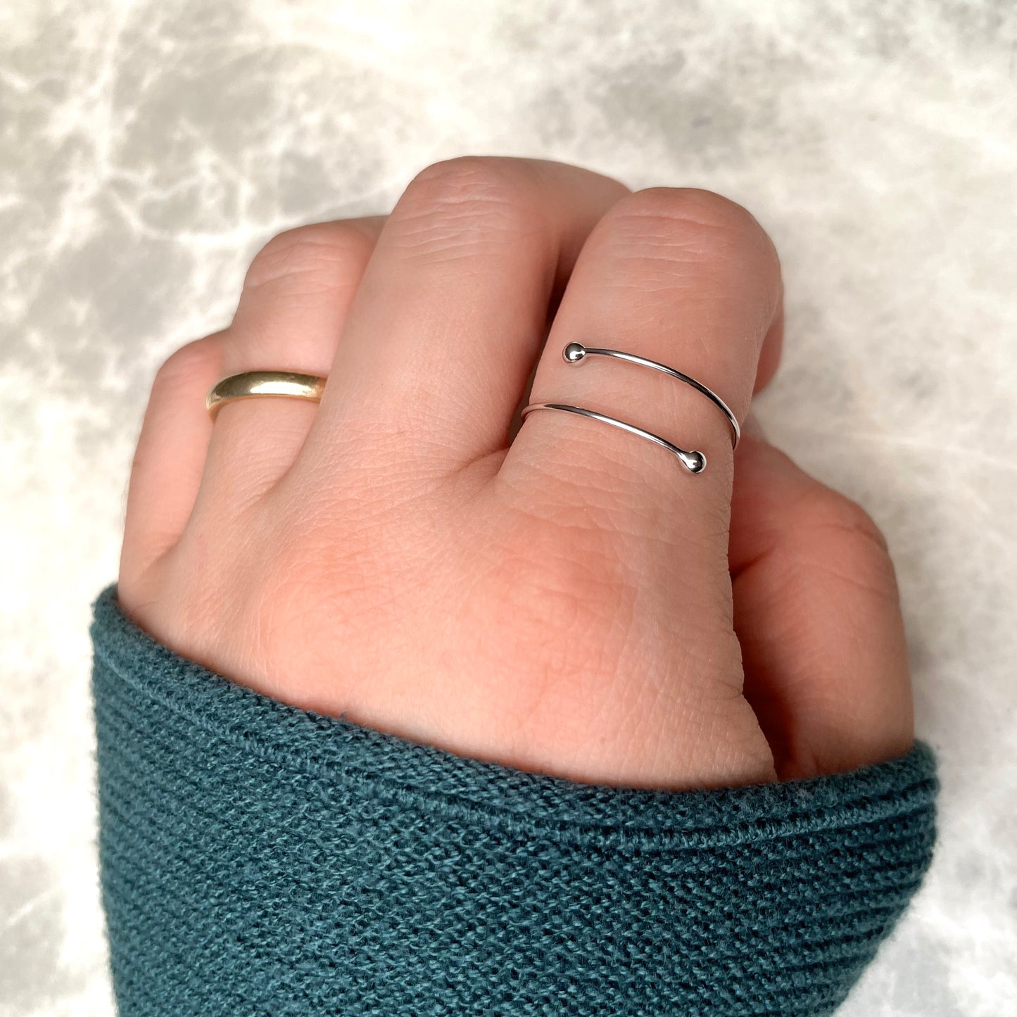 Dainty fidget ring  in silver worn by a person with teal sleeve