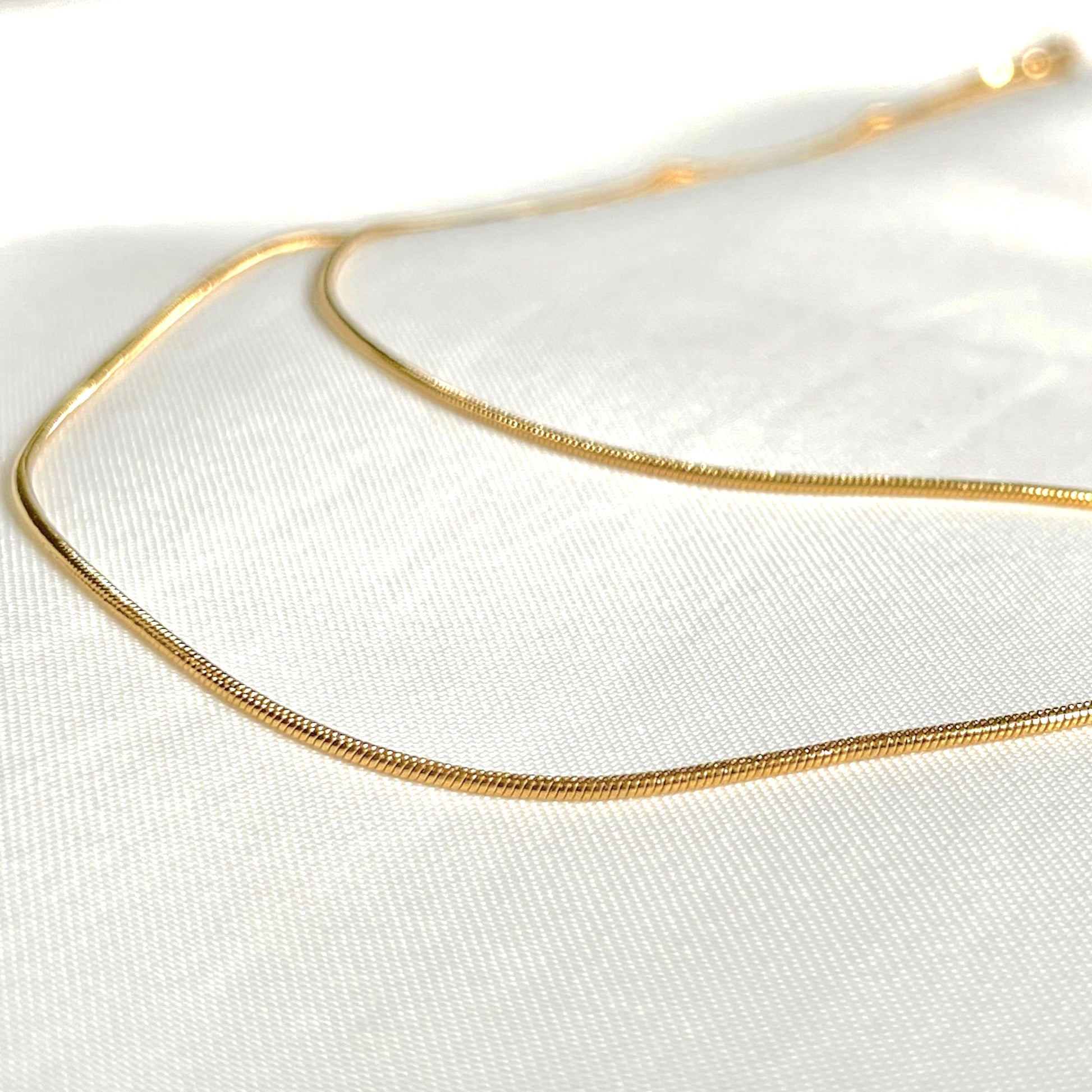 Layered gold necklace on a white fabric background