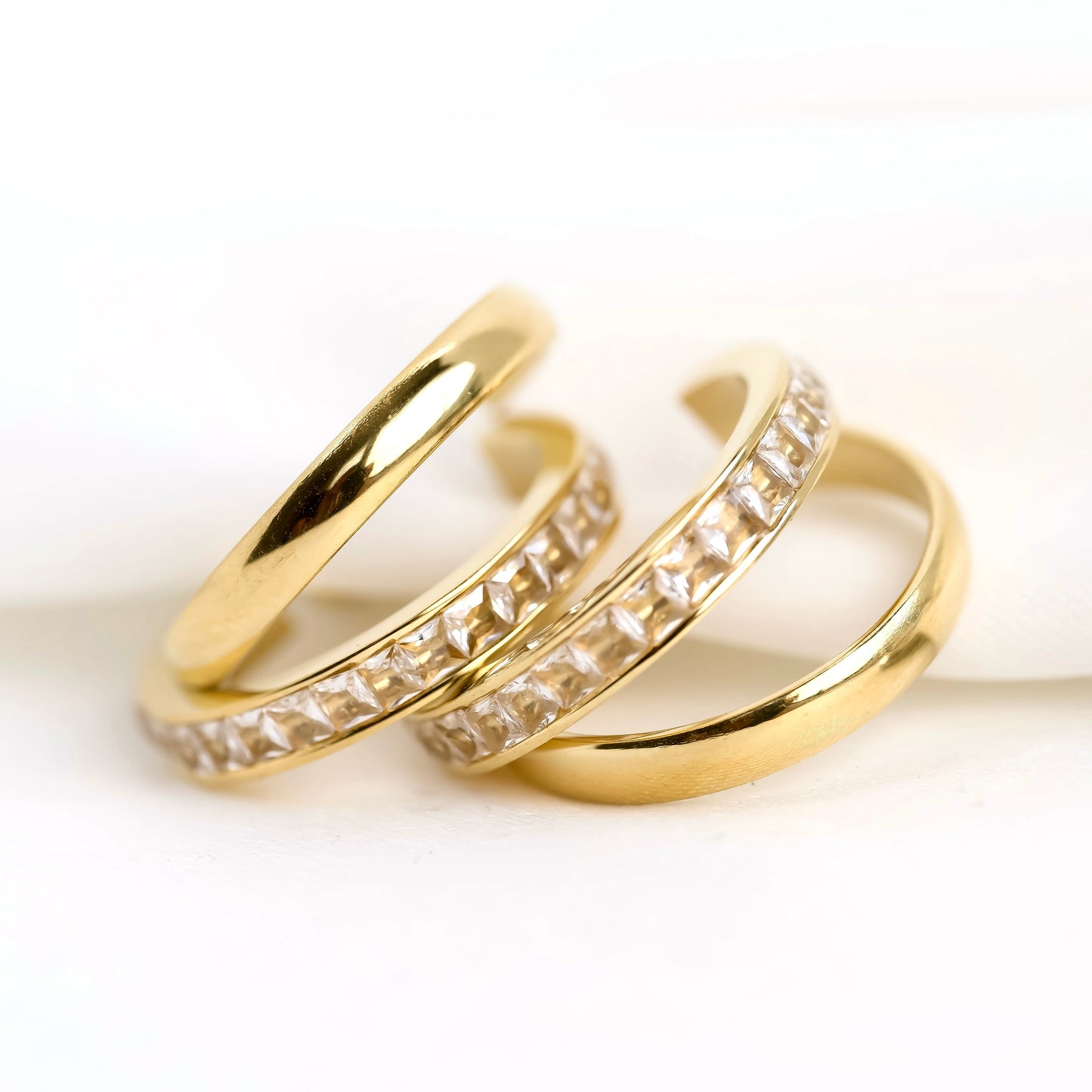 Two gold hoop earrings with channel set crystals on a white background