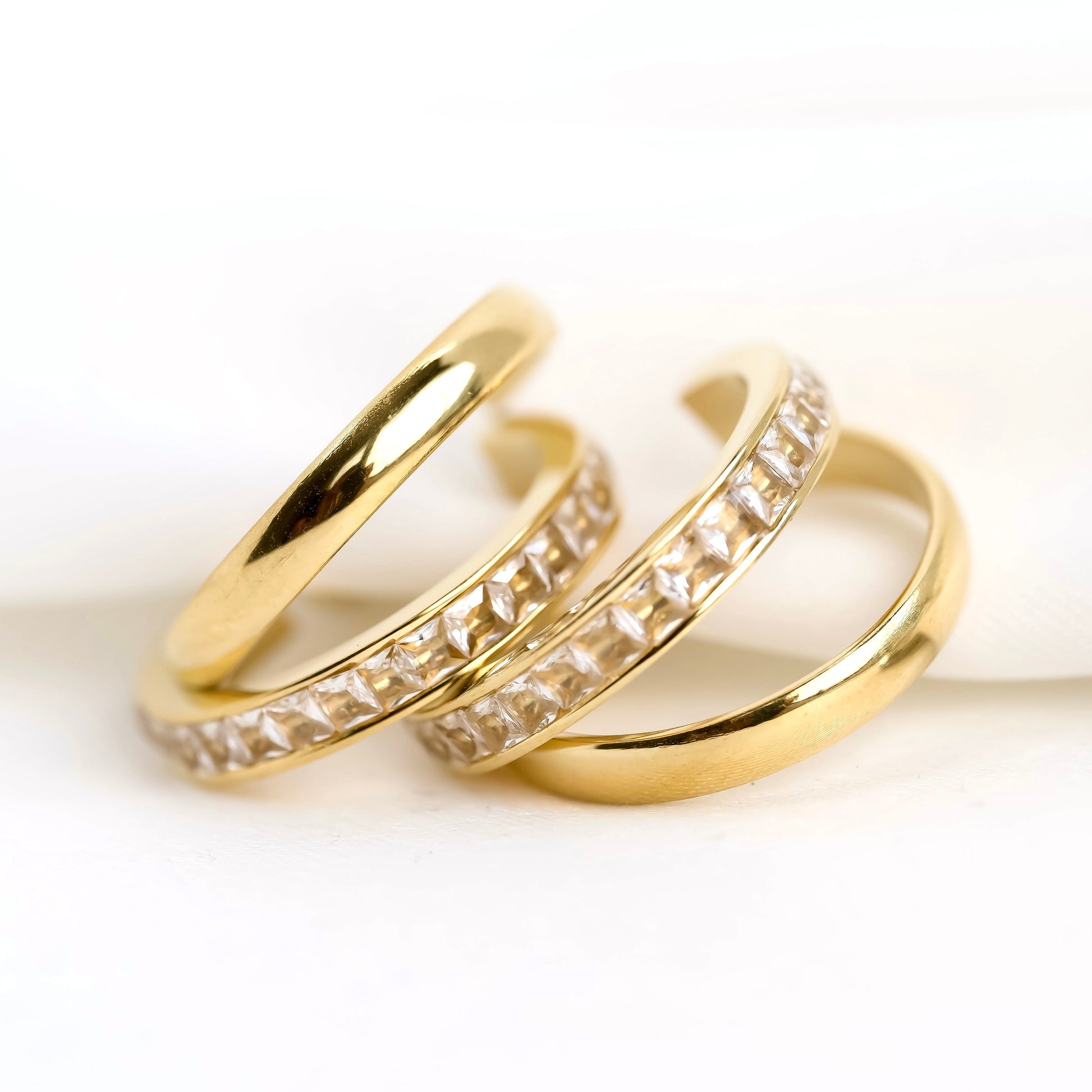 Two gold hoop earrings with channel set crystals on a white background