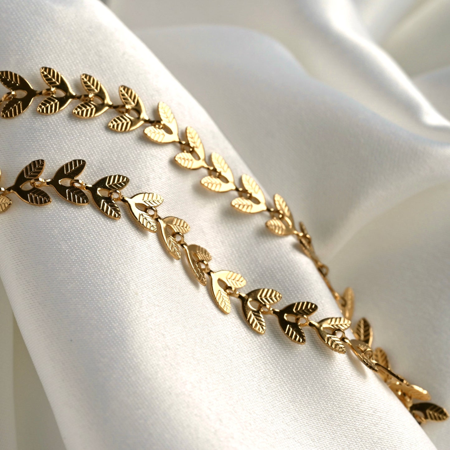 Gold textured leaf-patterned chain on a white fabric background