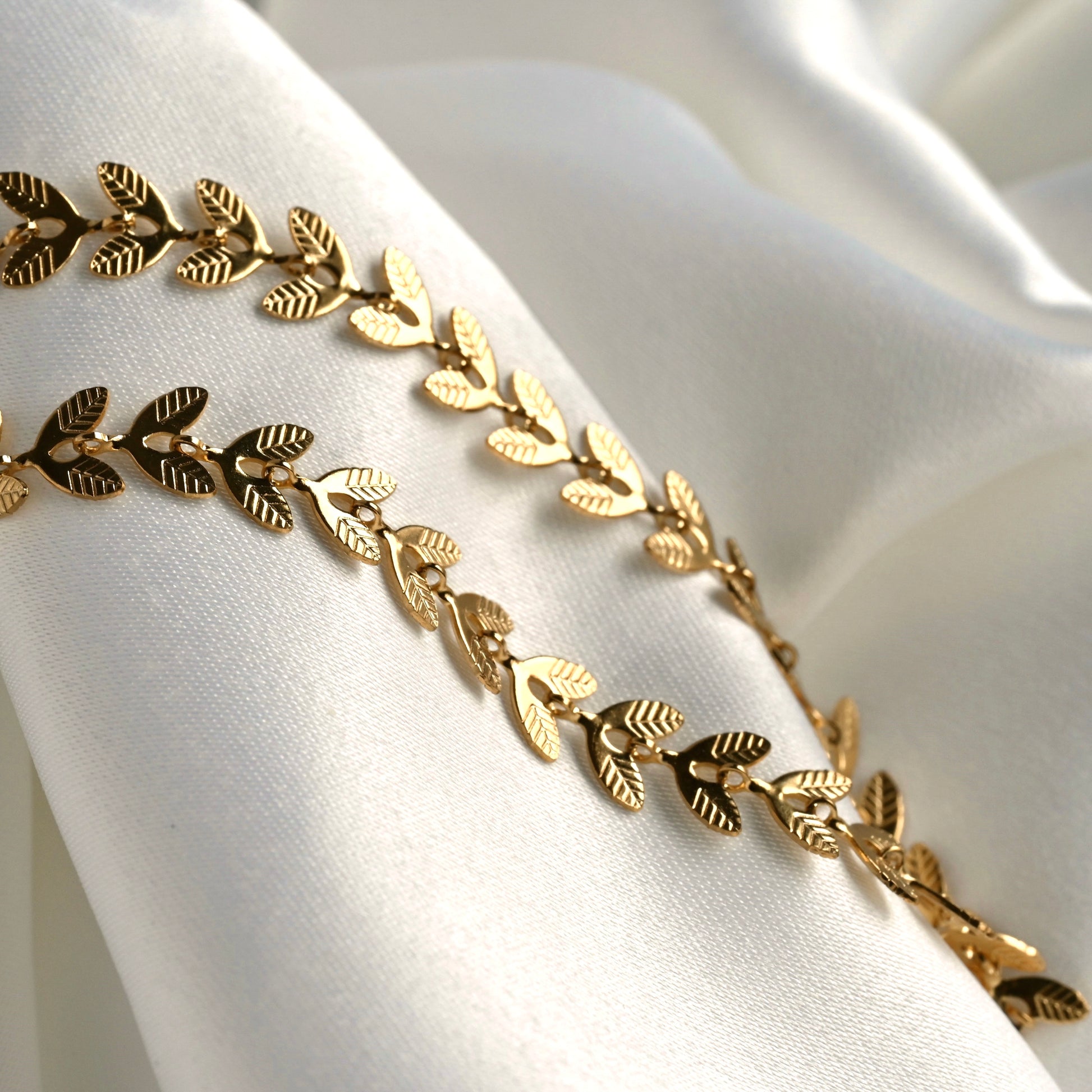 Gold textured leaf-patterned chain on a white fabric background
