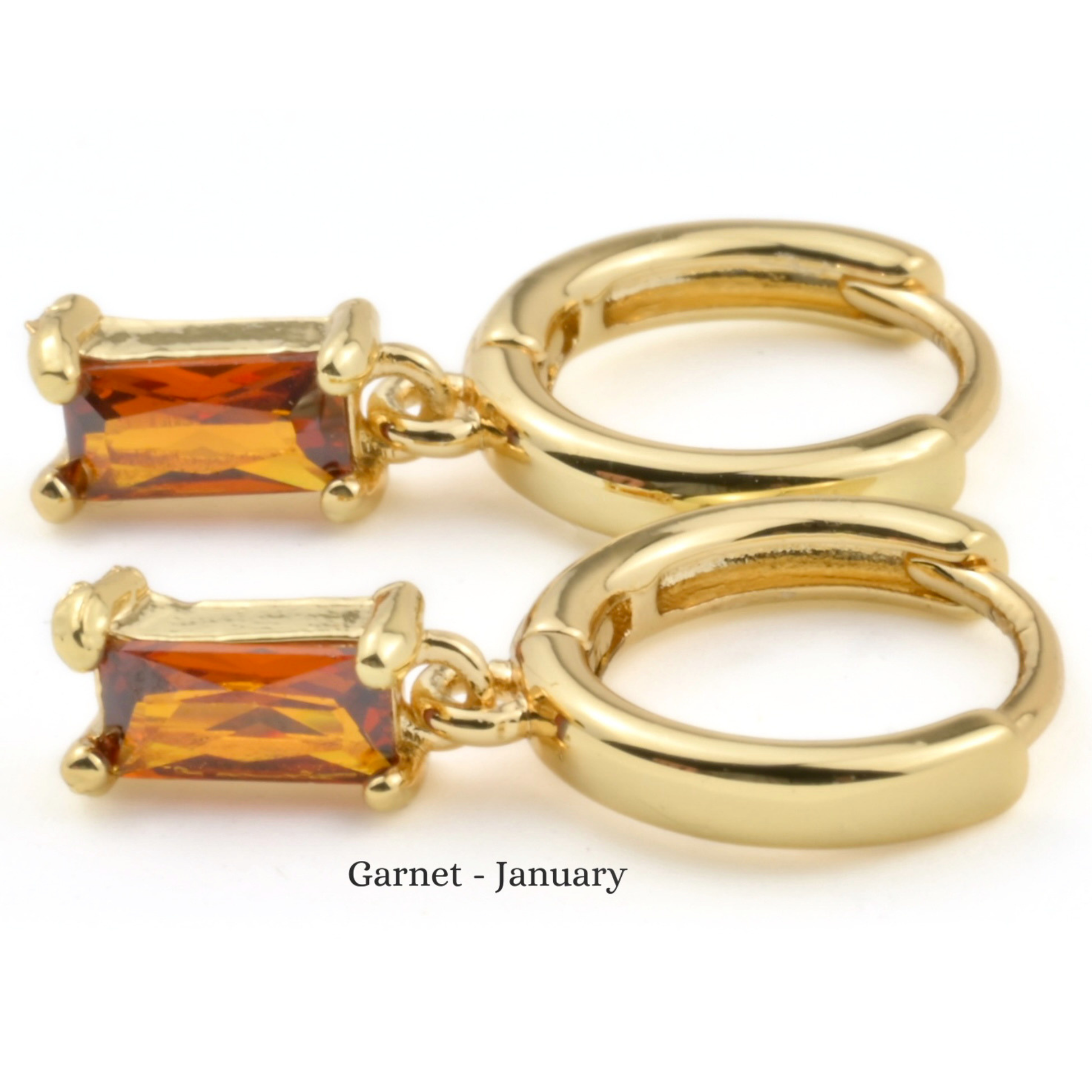 Gold hoop earrings with garnet stones on a white background