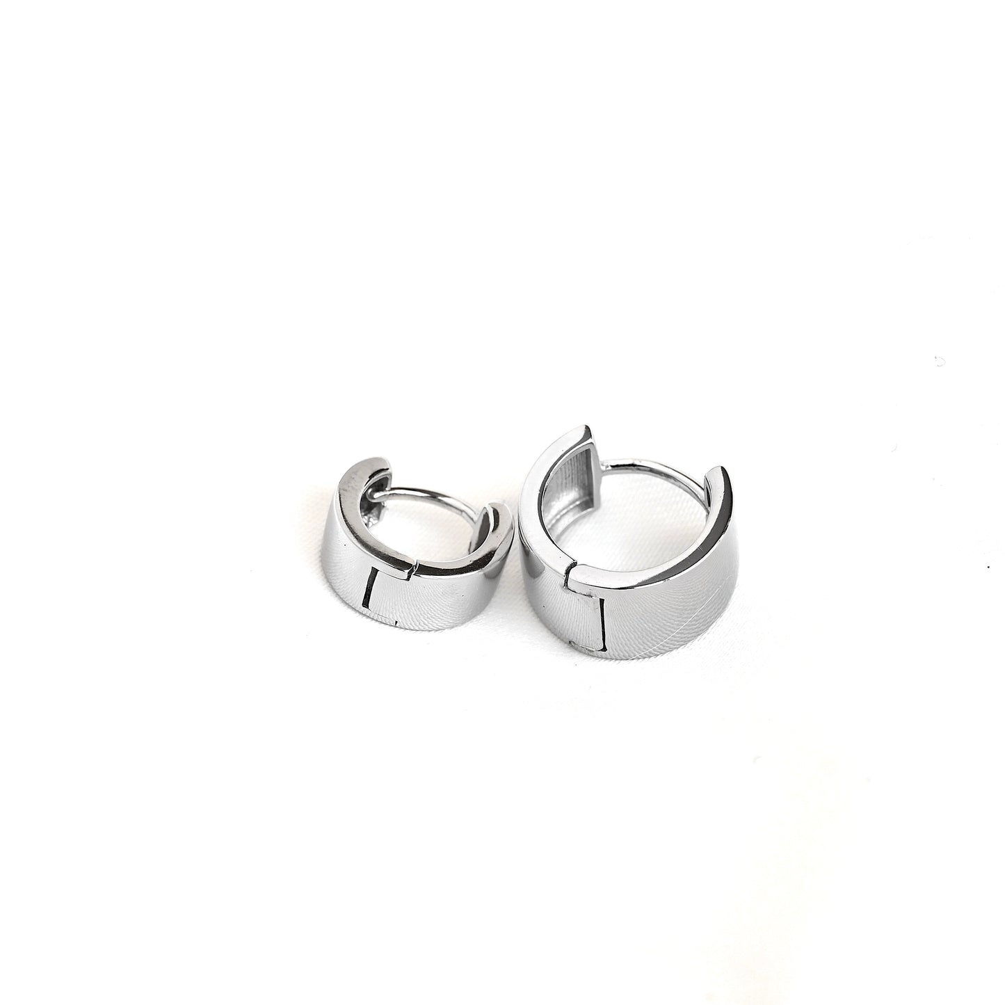 Top view of a pair of silver-toned sterling silver huggie hoop earrings with a polished design, displayed on a clean white background.