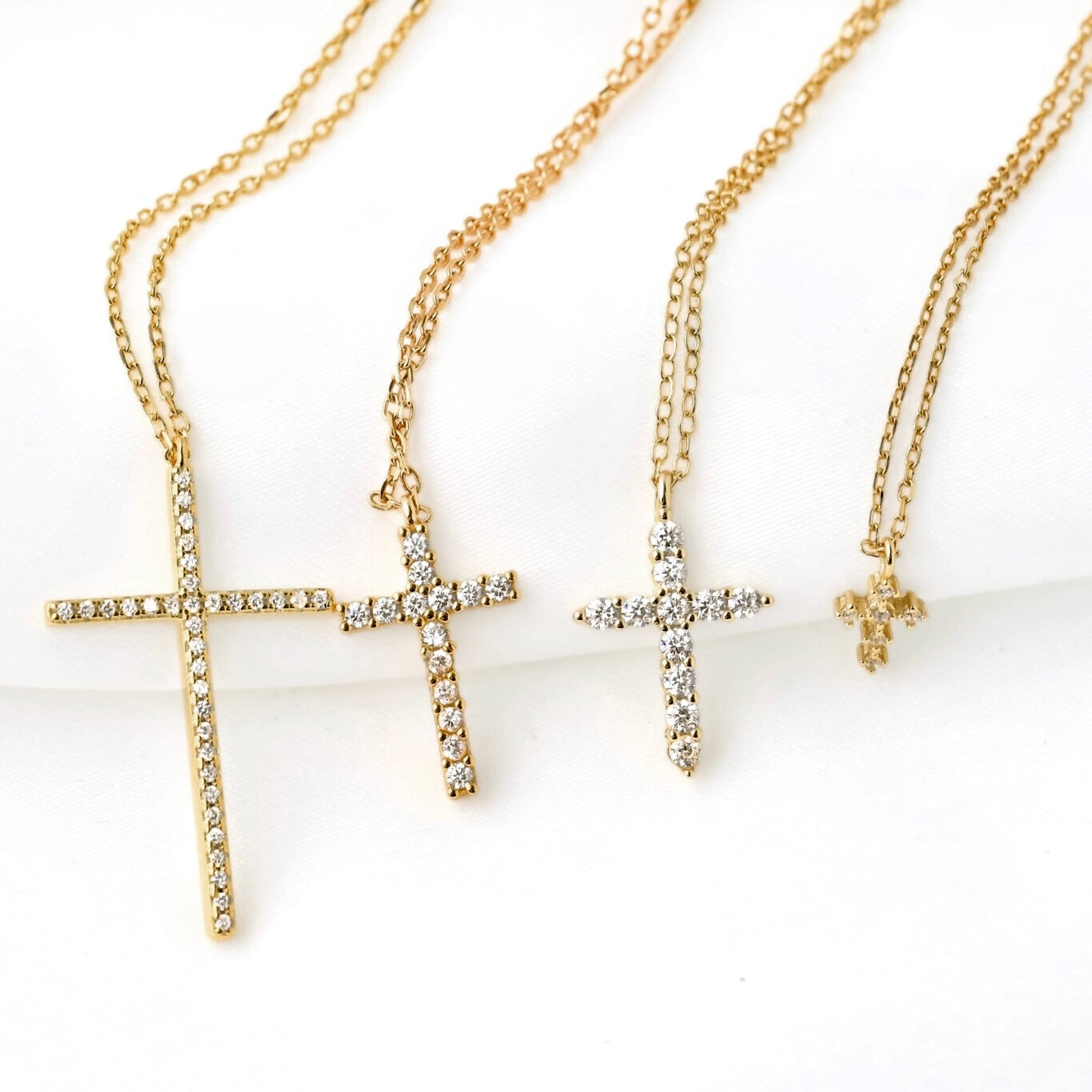 Gold CZ cross necklaces with super tiny to oversized pendants on a white background