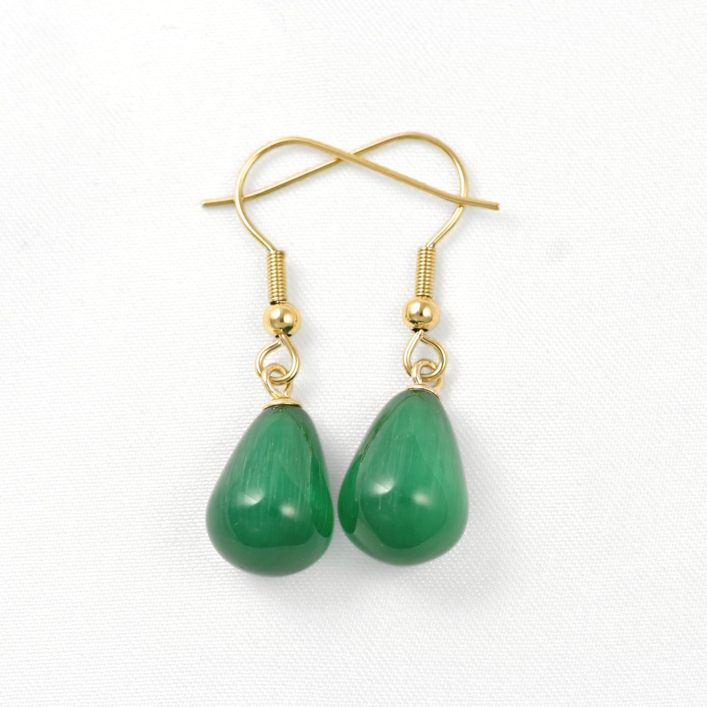 A pair of gold-tone dangle earrings with teardrop-shaped green stone pendants, shown on a clean white background.