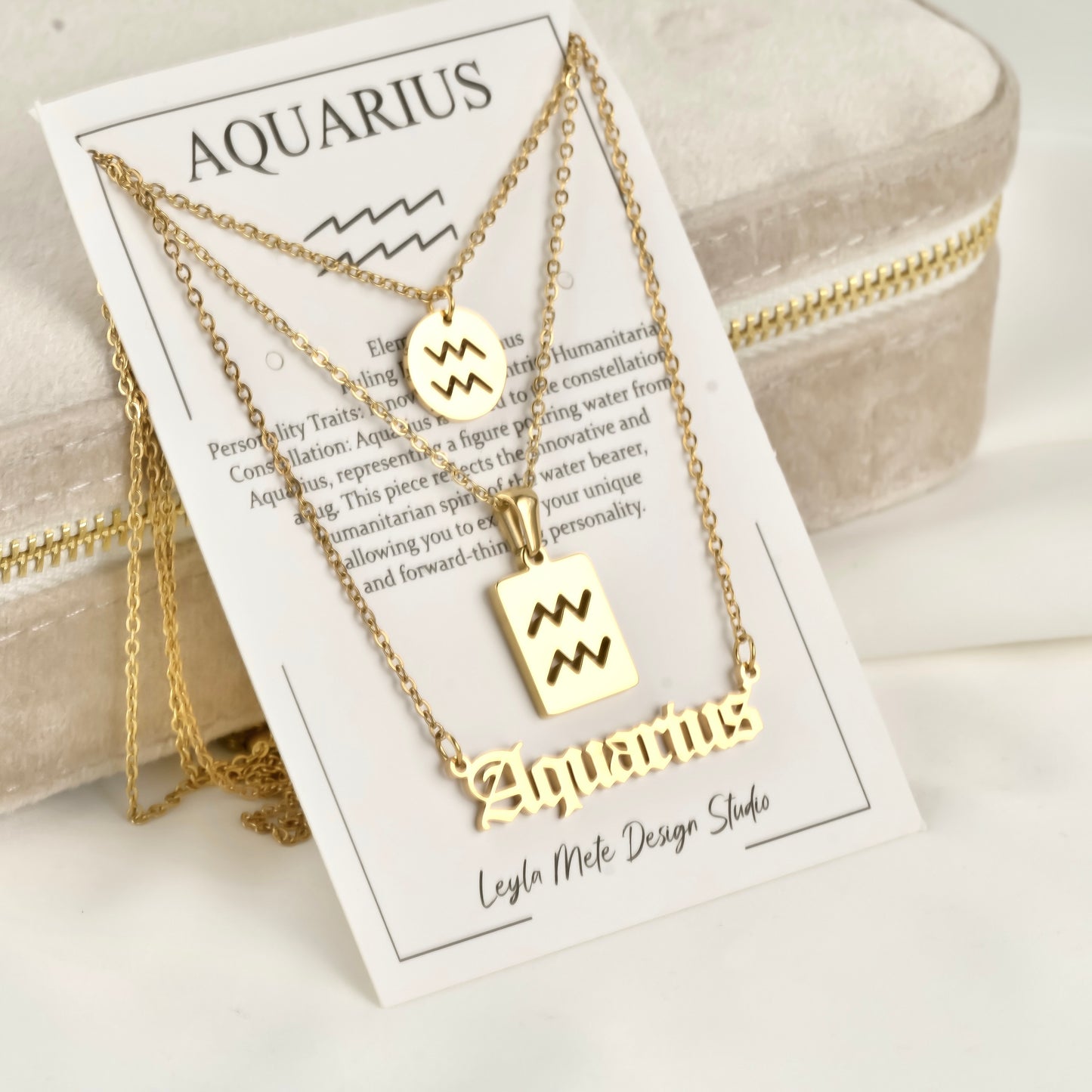 Gold Aquarius necklaces on a branded card with product details.
