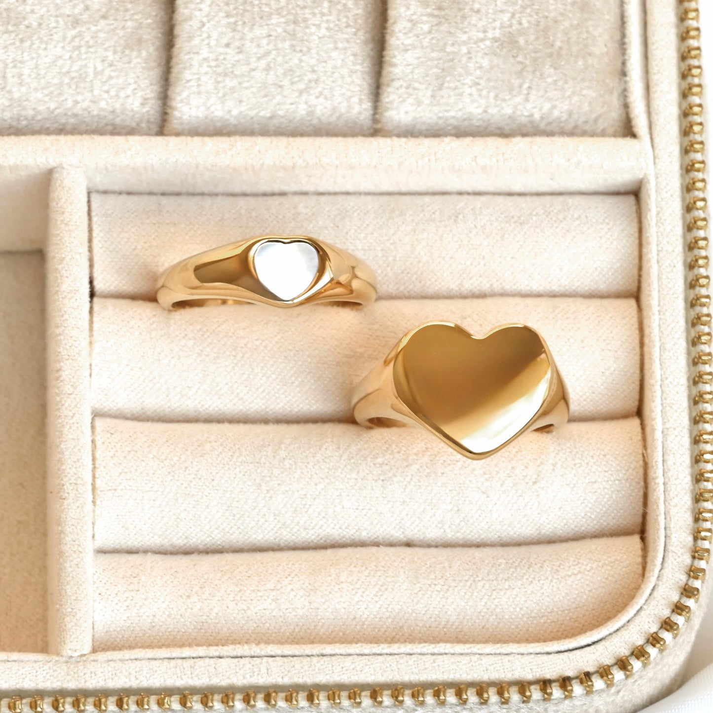 Two gold heart-shaped rings in a eige jewelry box