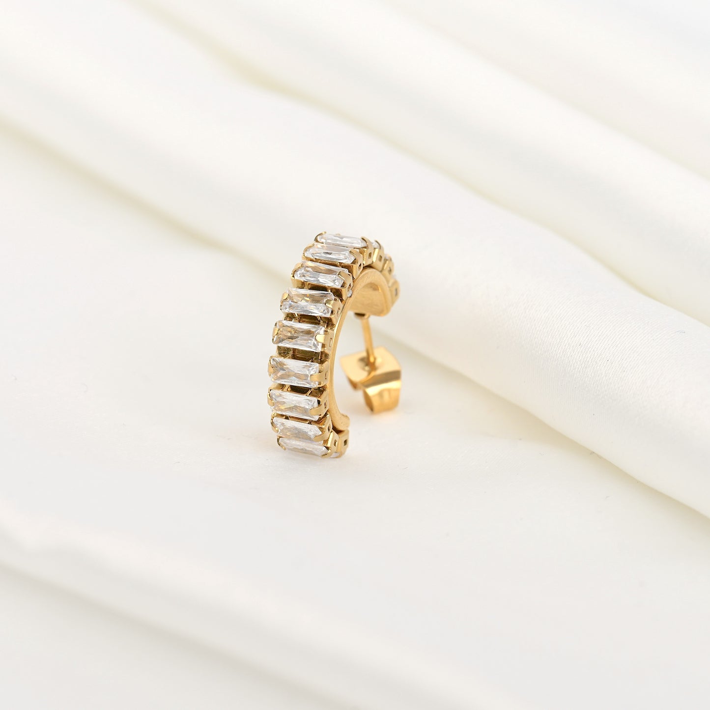 Close- up view of Gold diamond hoop earring with clear rhinestones on a white background