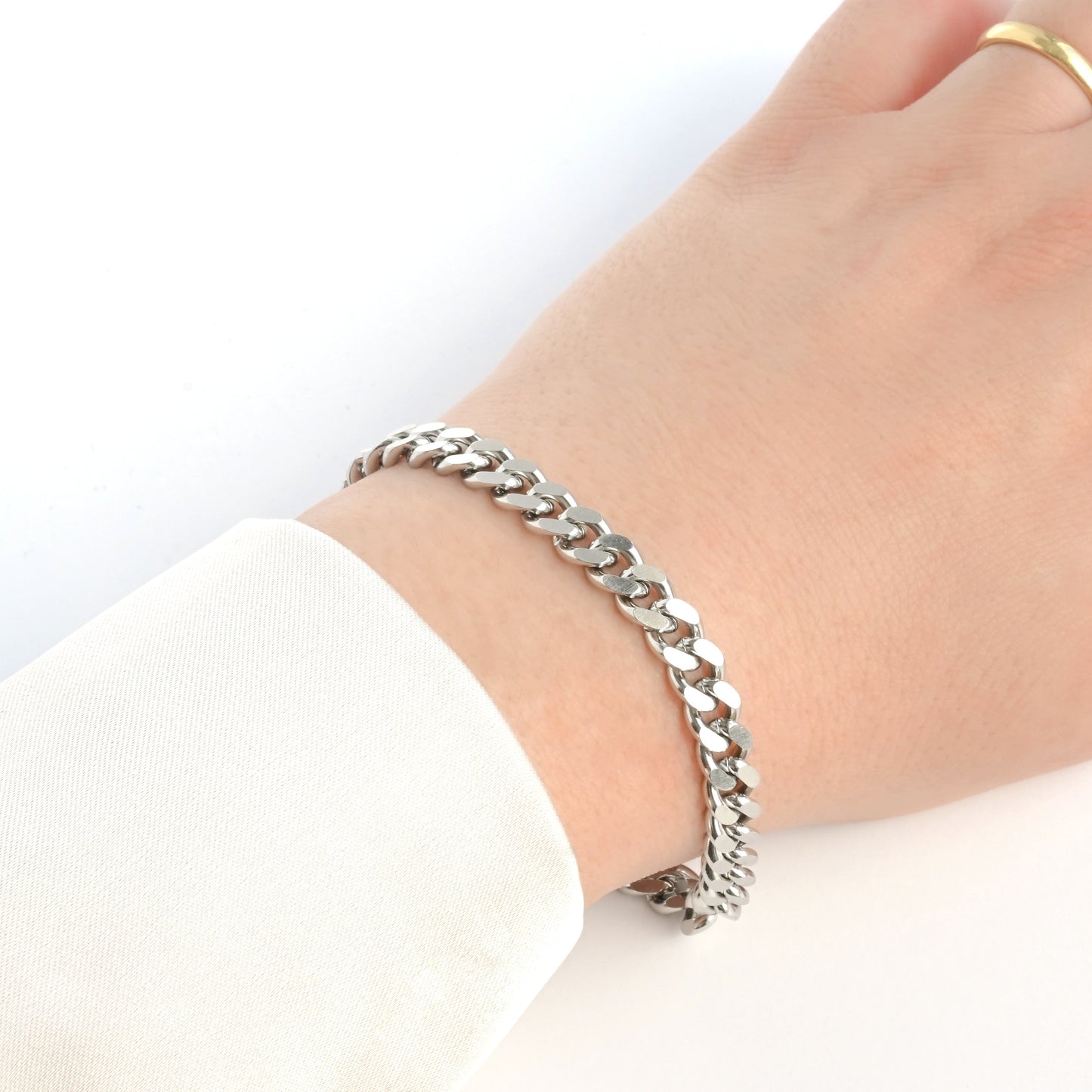 7mm Silver cuban chain bracelet on a wrist with a plain background