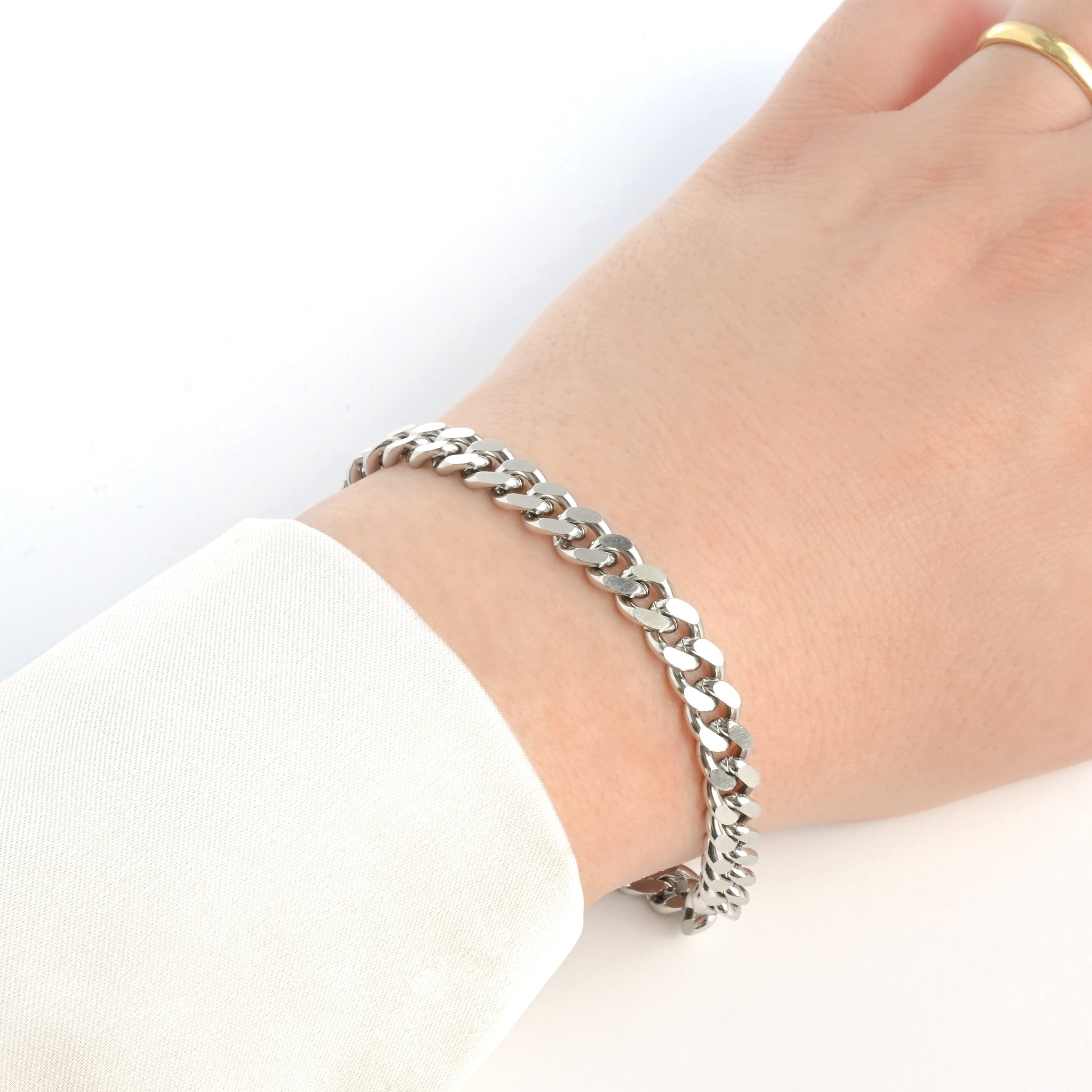 7mm Silver cuban chain bracelet on a wrist with a plain background