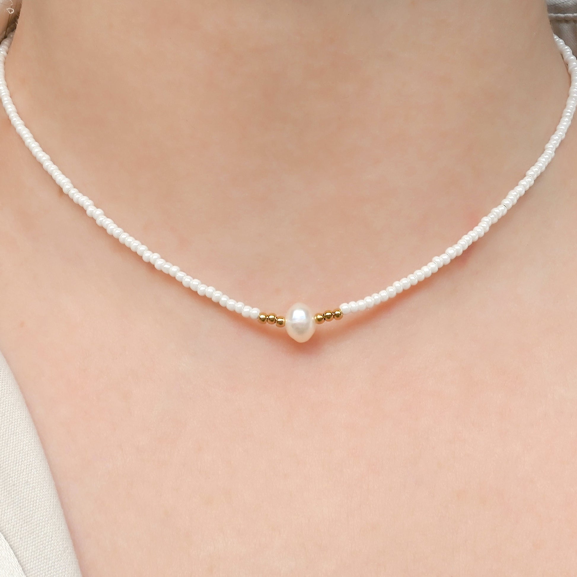 Pearl necklace with gold accents on a person's neck