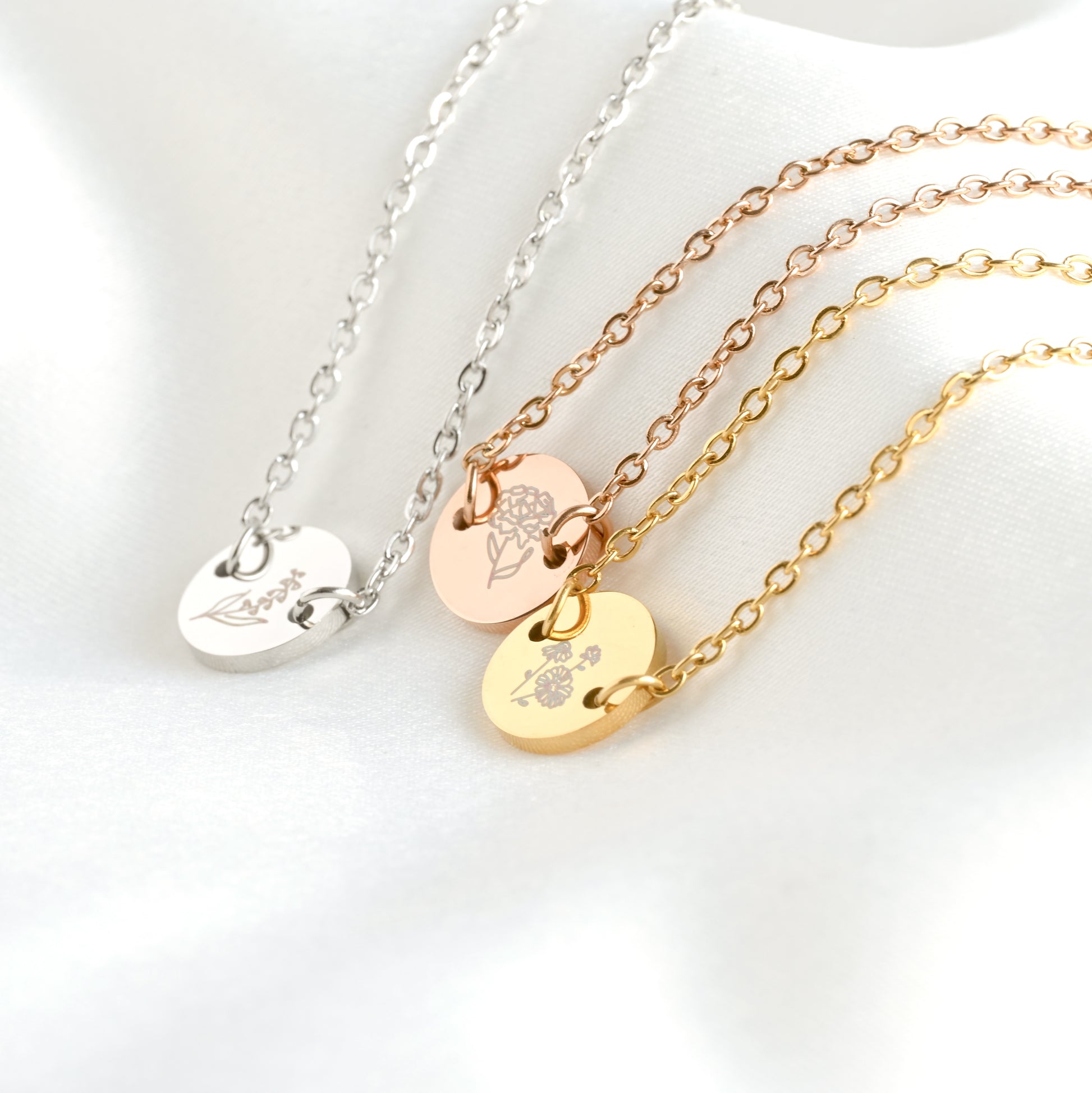 Three birth month bracelets in silver, rose gold, and gold on a white background