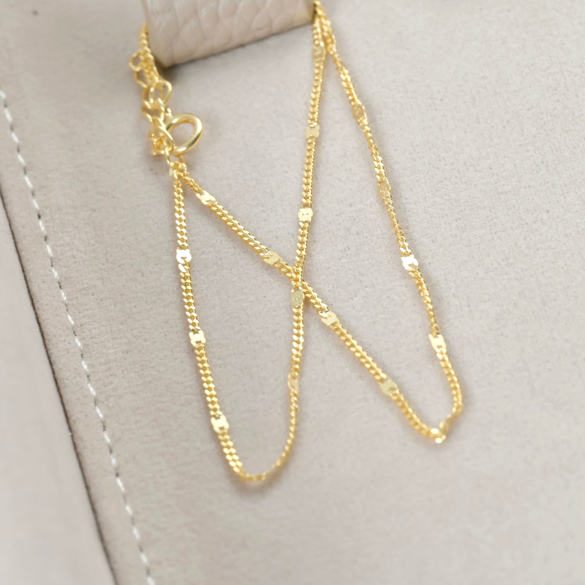 Gold chain bracelet on a light gray surface