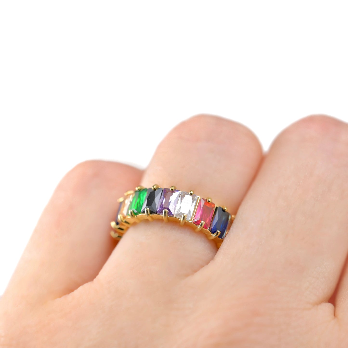 Ring with multicolored gemstones on a finger against a white background