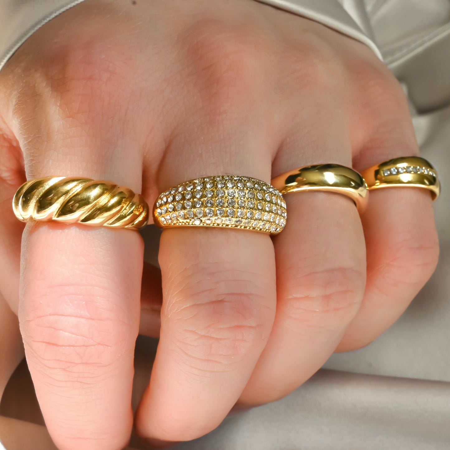 Three gold rings on a person's fingers under direct sunlight