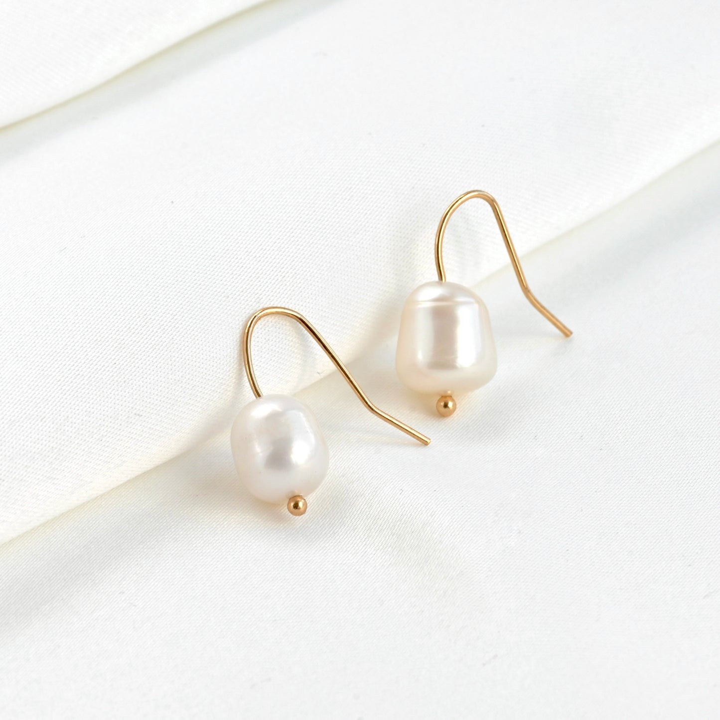 Baroque pearl earrings with gold hooks on a white background