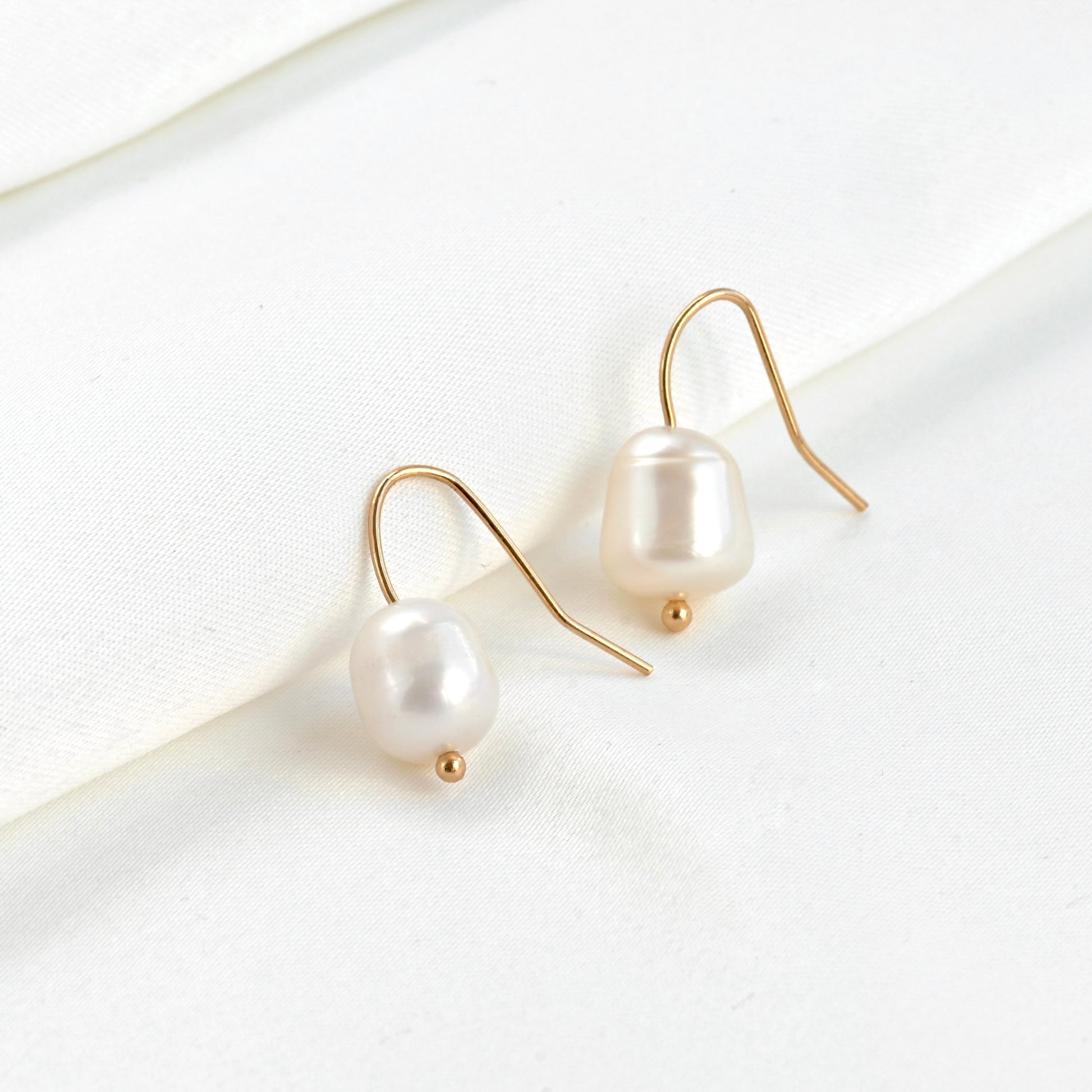 Baroque pearl earrings with gold hooks on a white background