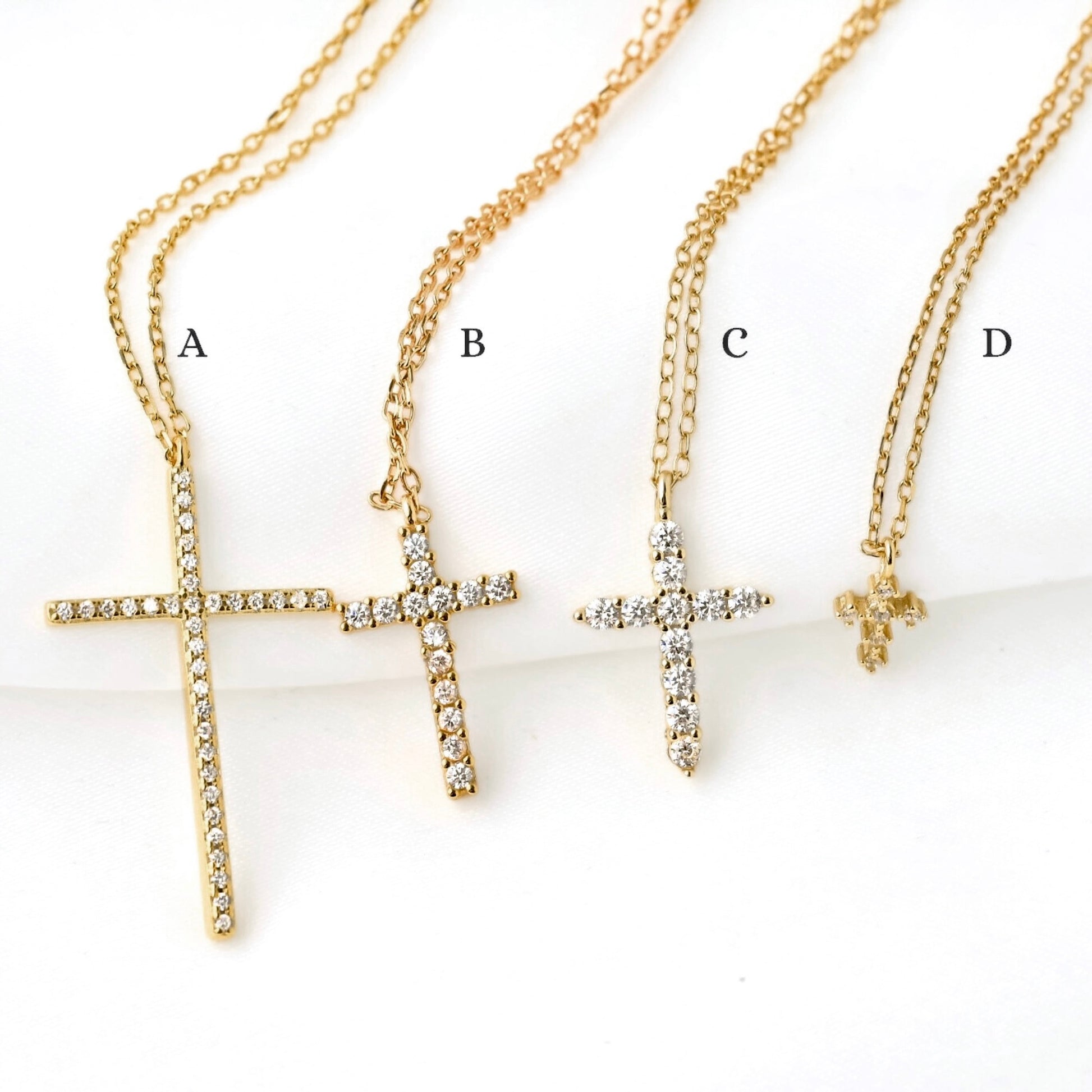 Four gold cross necklaces labeled A, B, C, and D on a white background