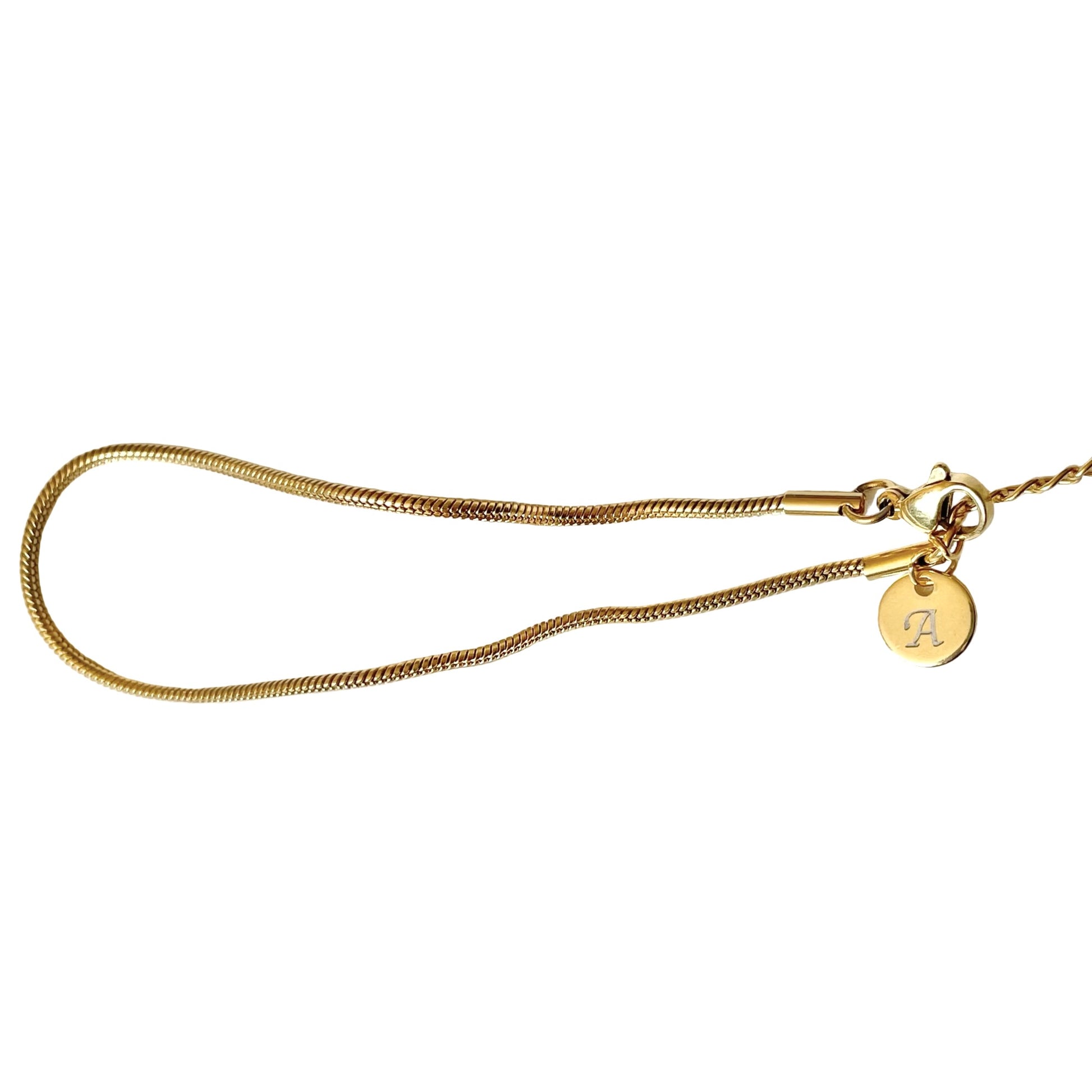 Gold skinny snake chain ankle bracelet personalized with a round initial charm on a white background