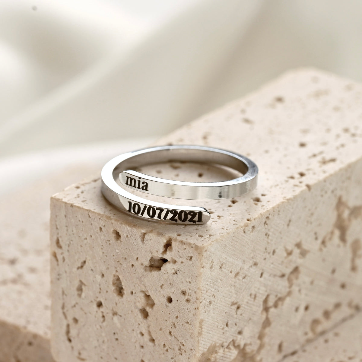 Silver ring with engraved text on a stone surface