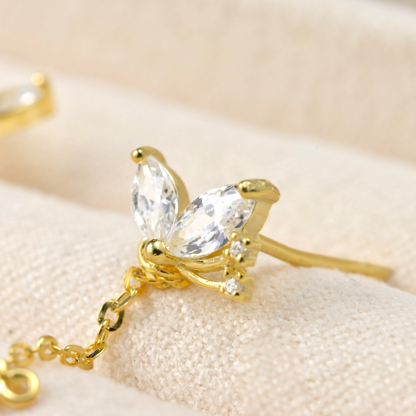 Close-up of  gold butterfly-shaped earring showing the intricate details of cubic zirconia stones.