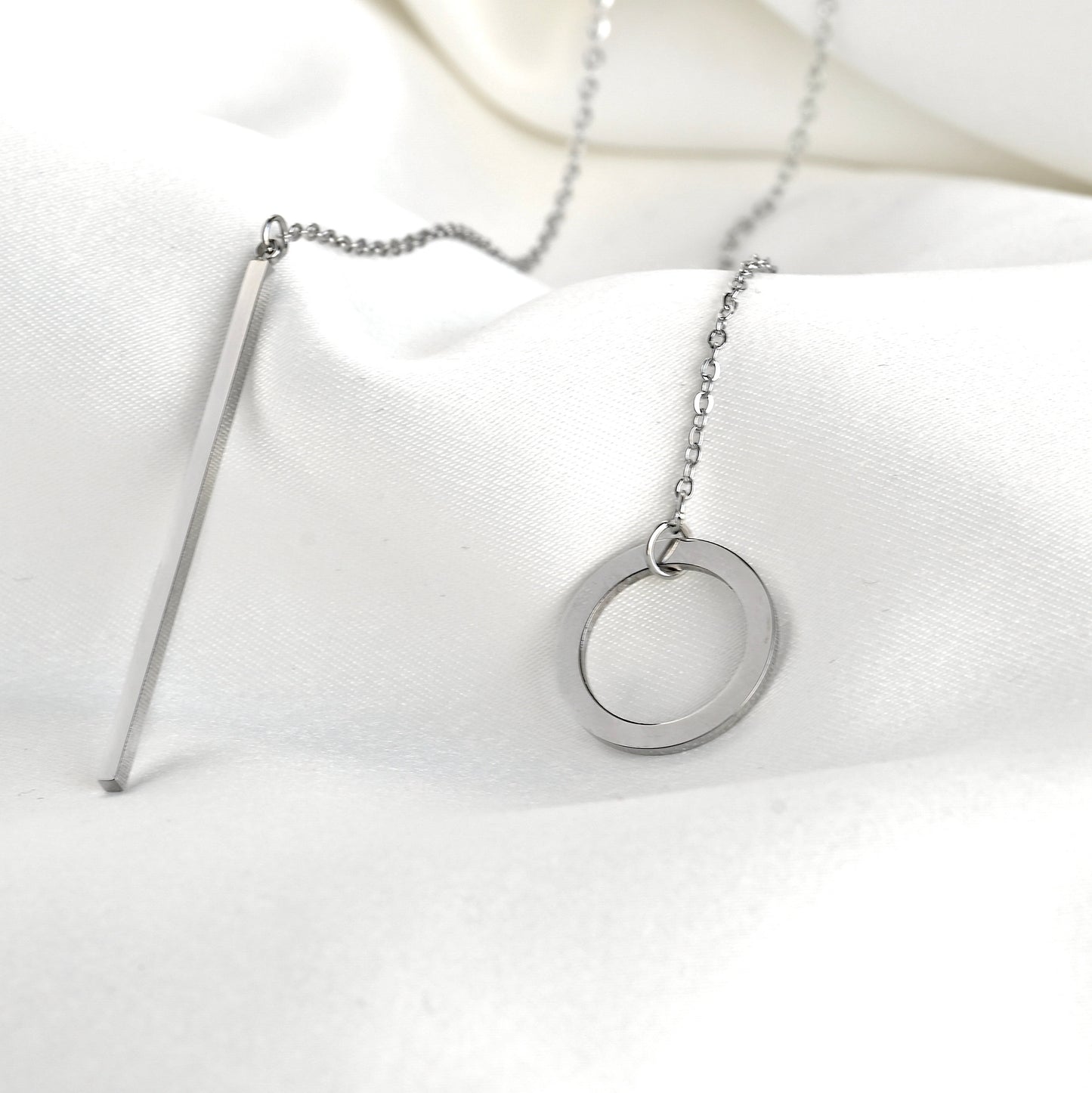 Silver necklace with a circle and bar side by side on a white background