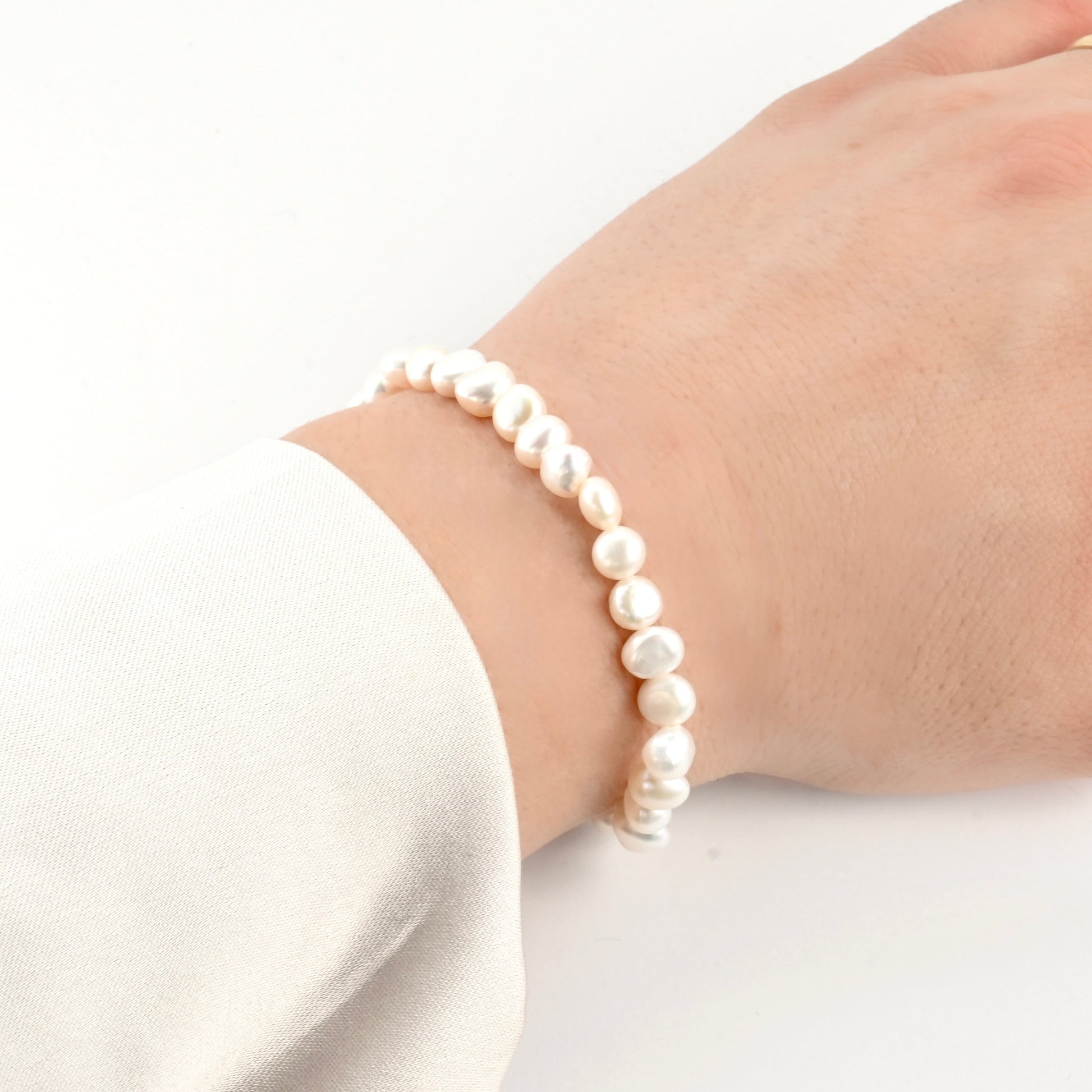 Full natural pearl bracelet on a person's wrist against a white background