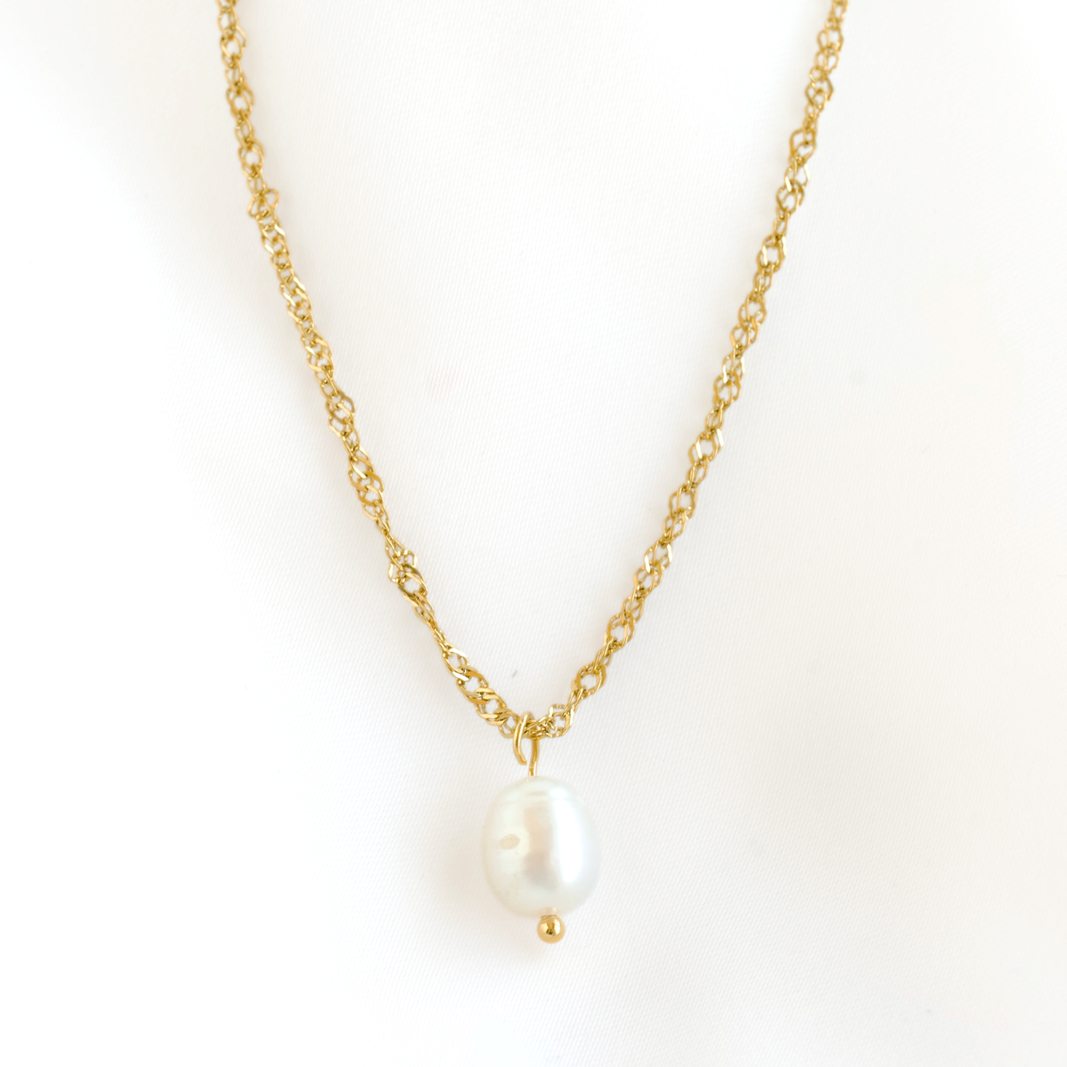 A delicate gold chain necklace featuring a single irregular, baroque-style white pearl pendant with a small gold bead accent below it, set against a plain white background.