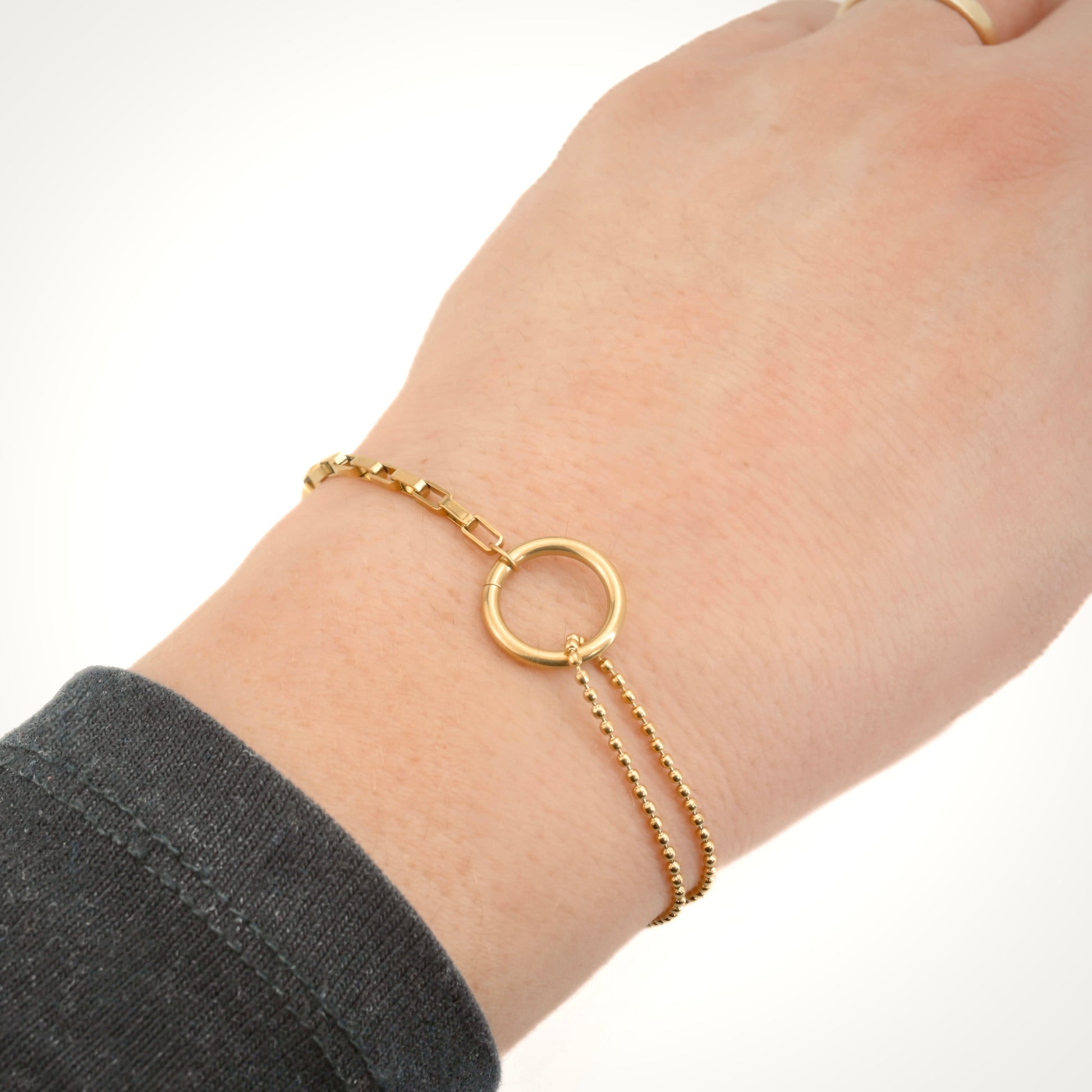Gold bracelet with a circular design on a wrist against a white background