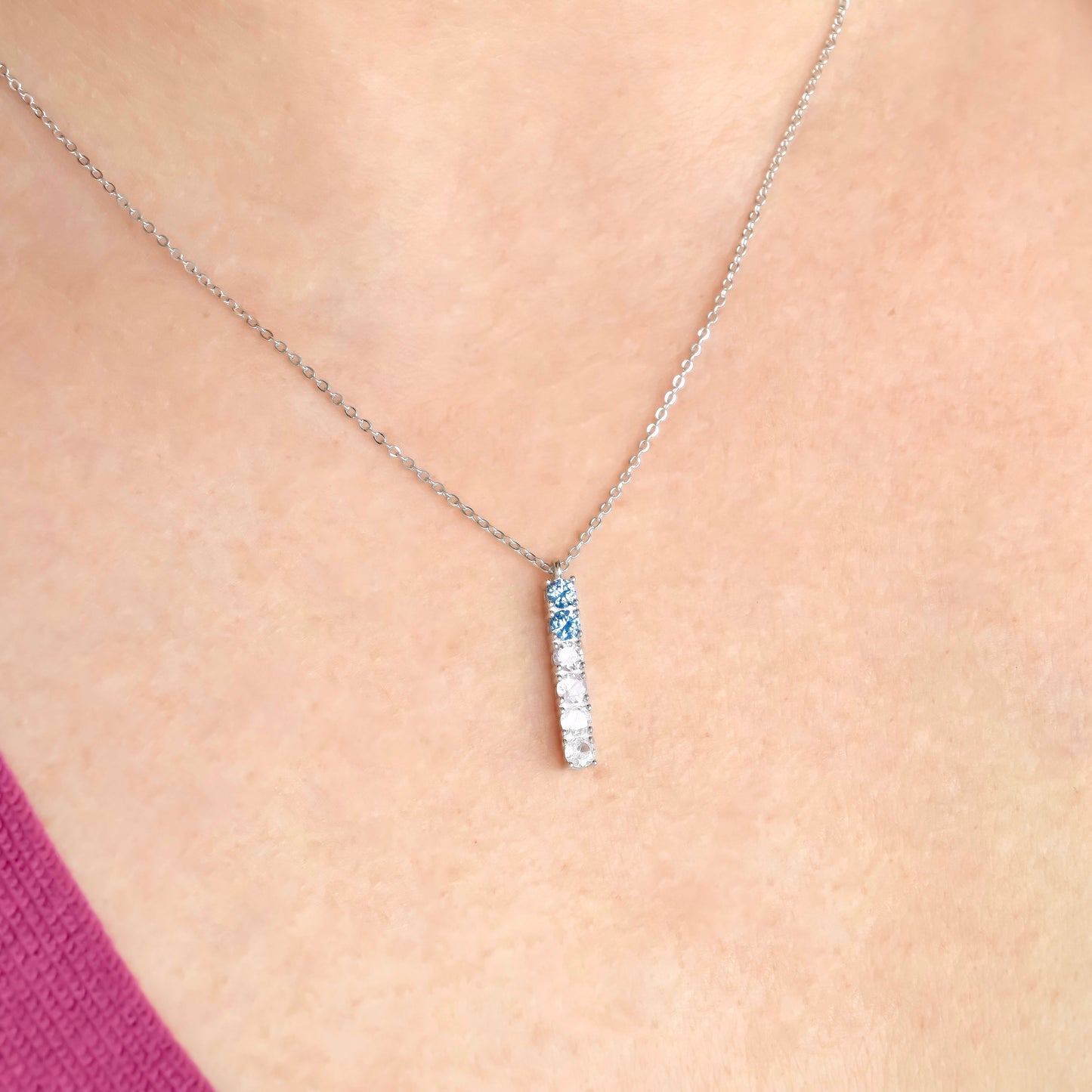 Silver necklace with a bar pendant on a person's neck