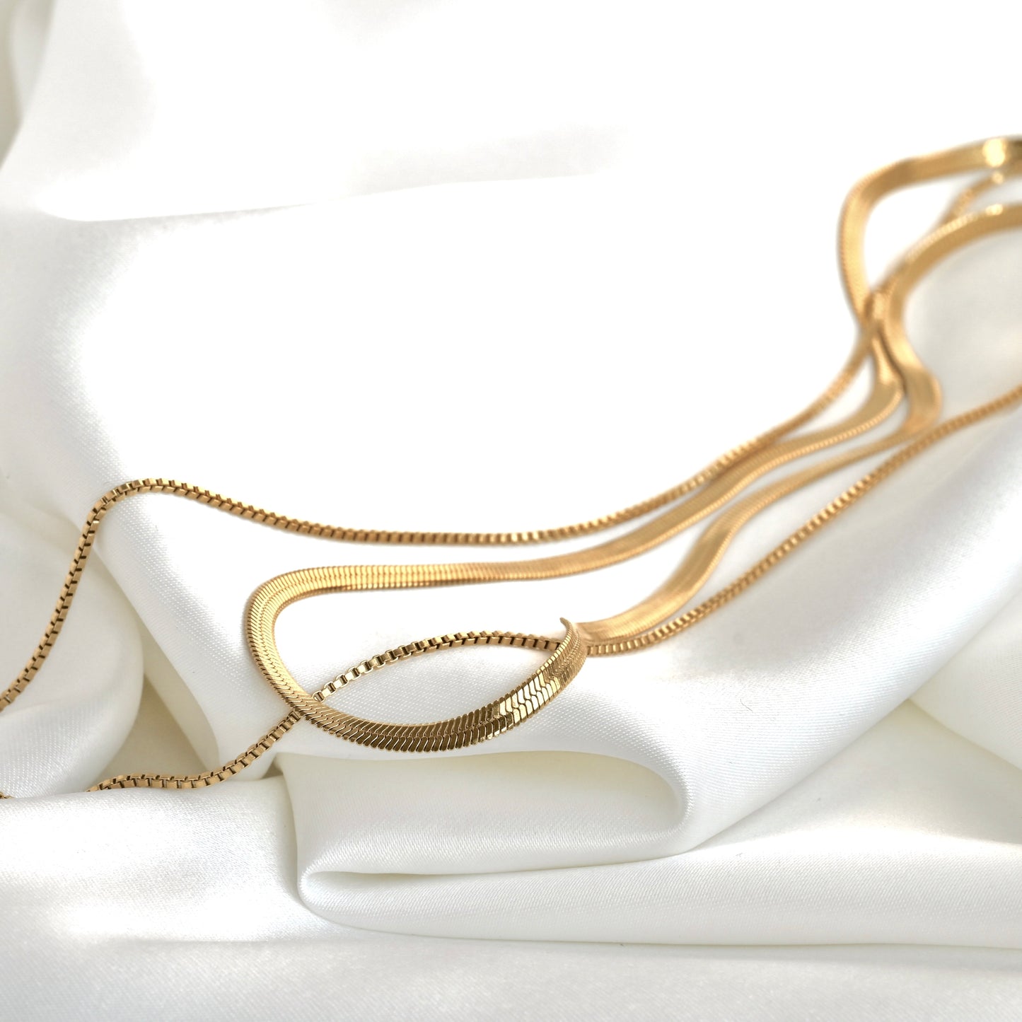 Double-layered Ggld necklace on a white fabric background