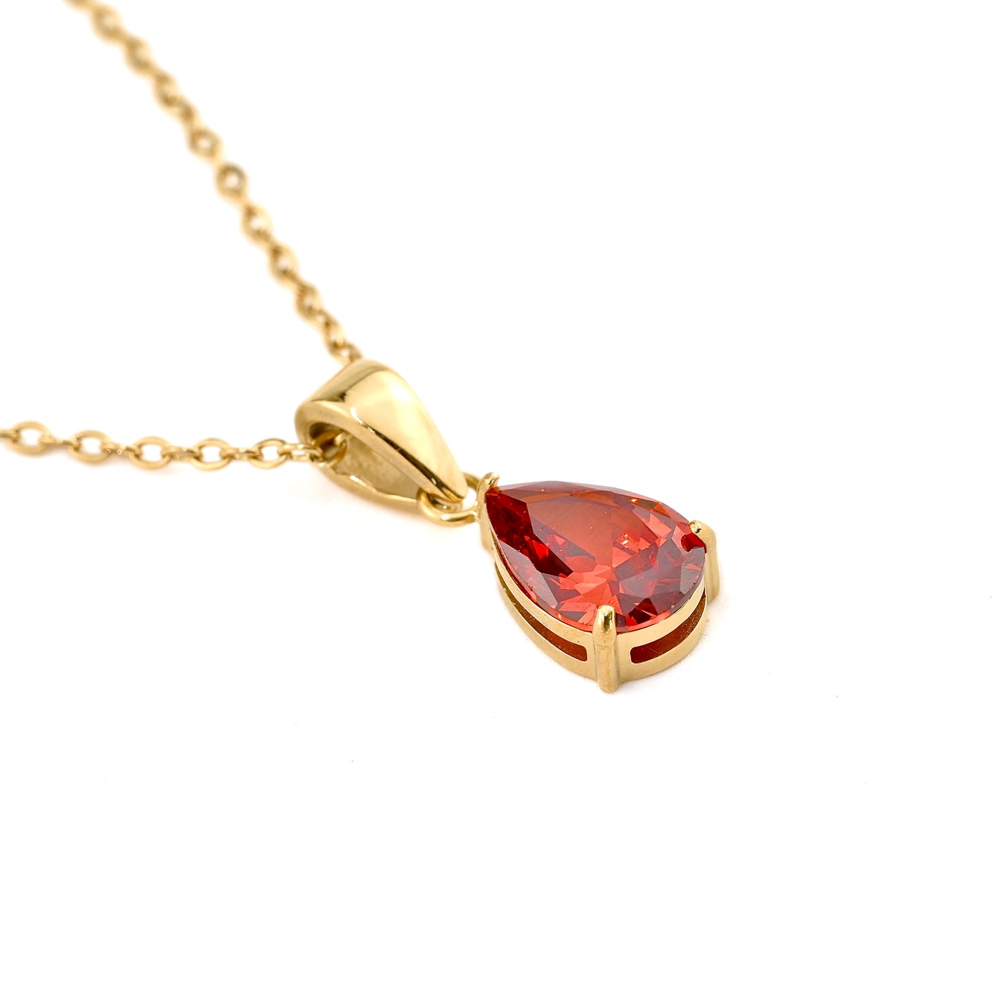 Gold necklace with a red teardrop-shaped gemstone pendant on a white background