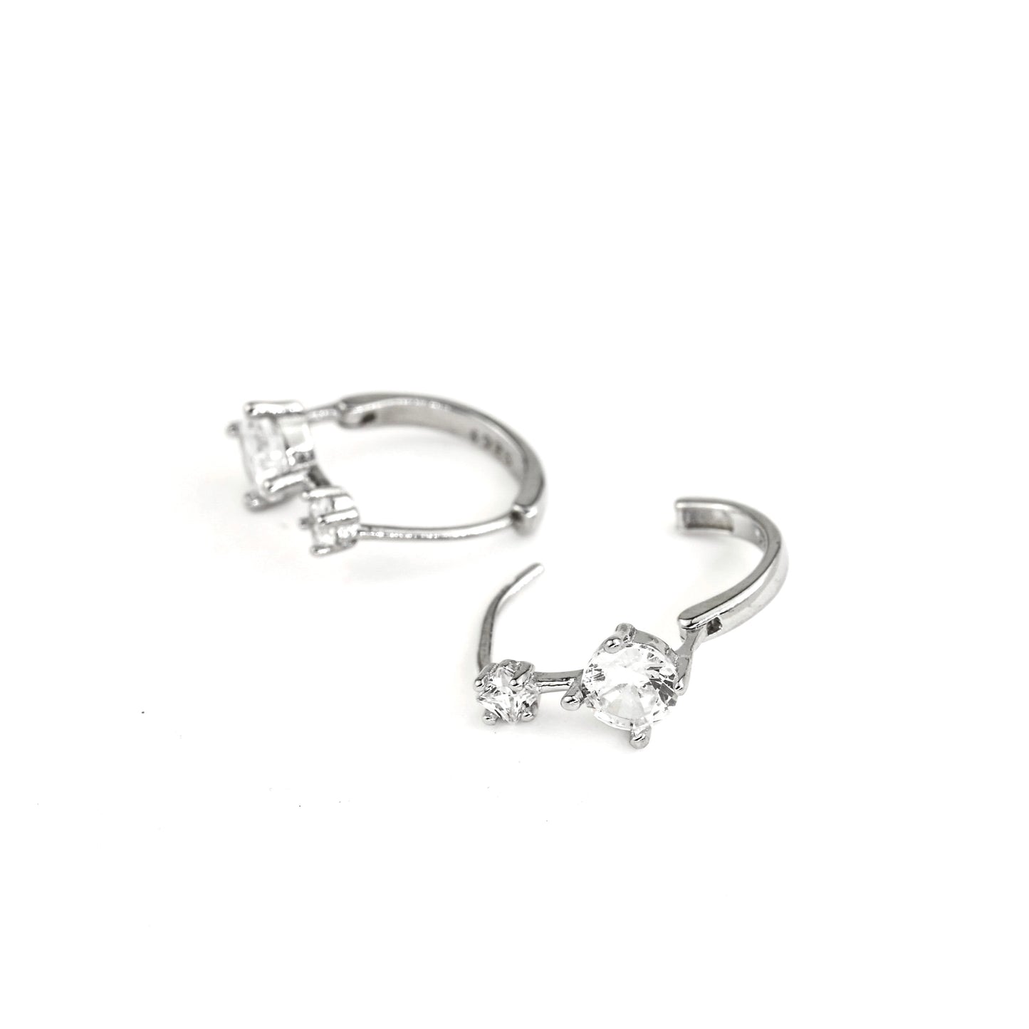 close up view of a Pair of silver hoop earrings with clear gemstones on a white background