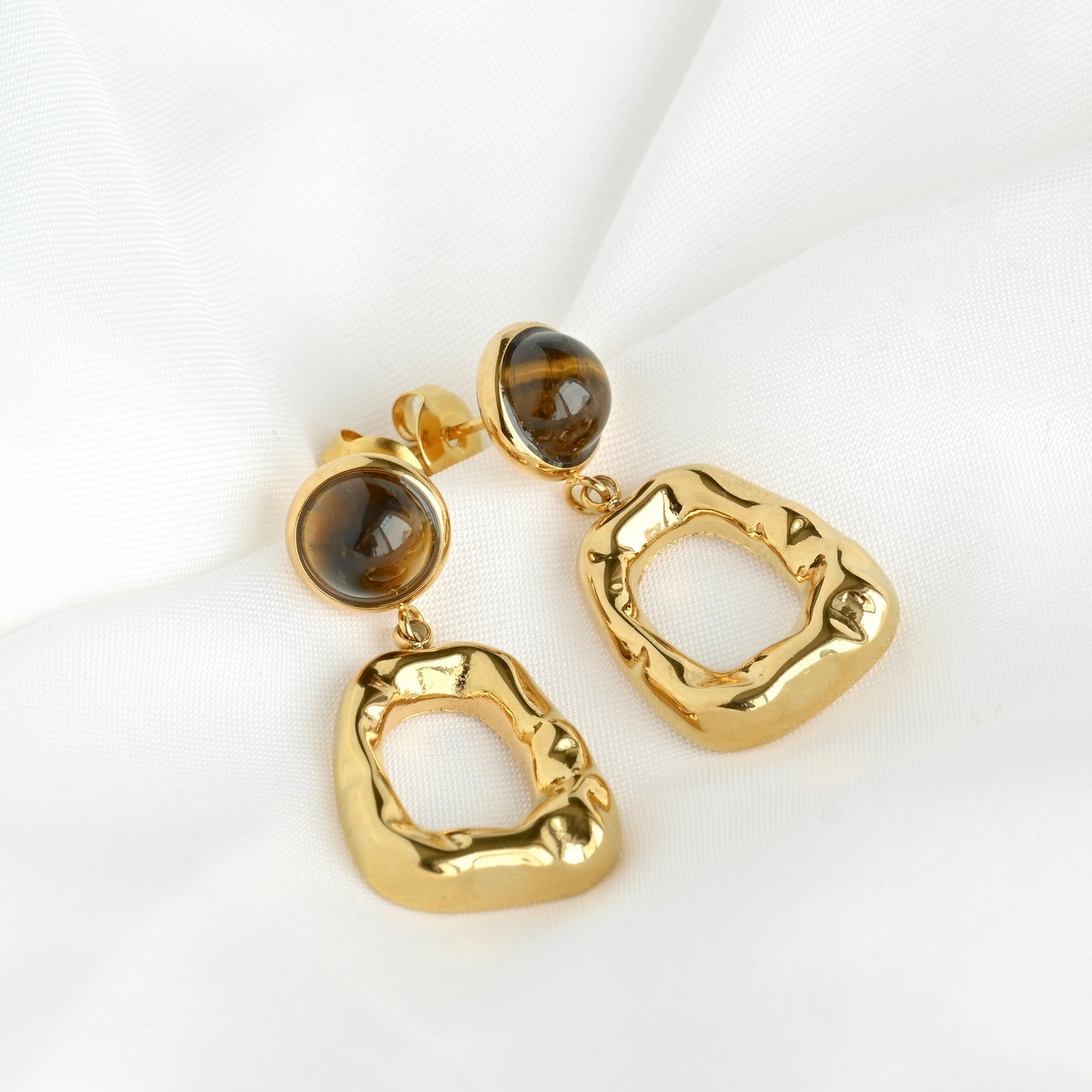 Gold earrings with brown gemstones on a white background