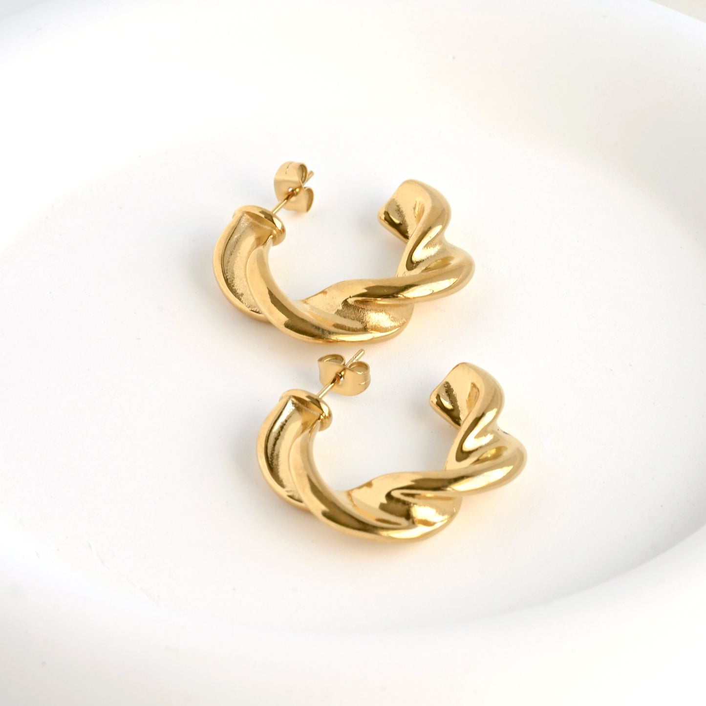 Gold twisted C hoops on a white background