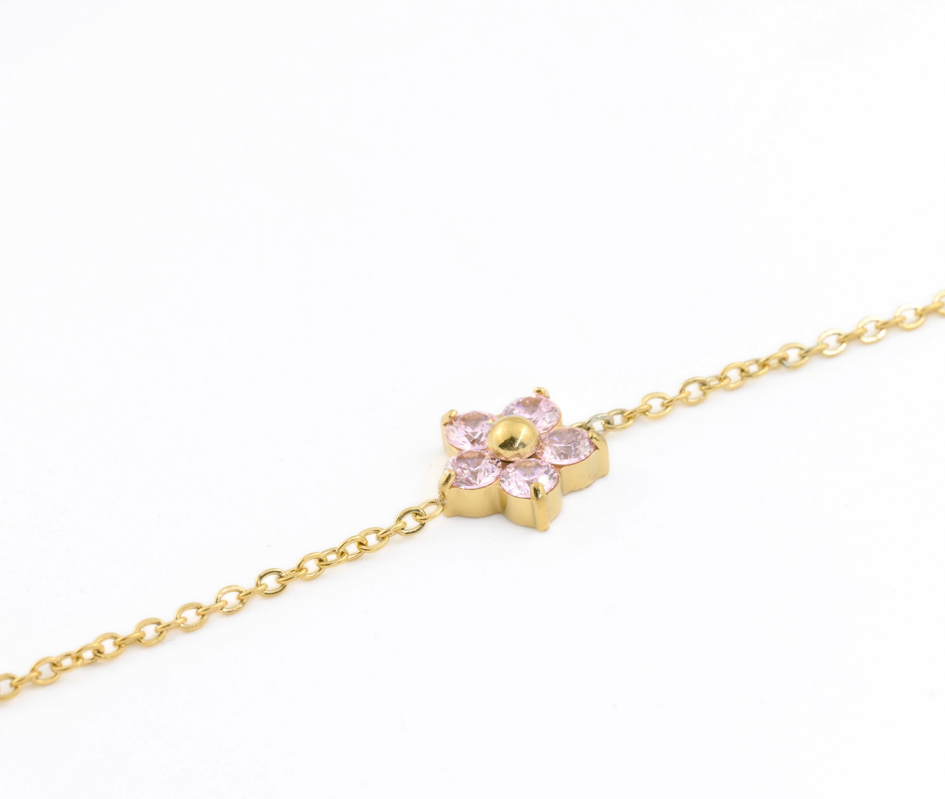 Gold bracelet with a flower charm featuring pink CZ petals on a white background