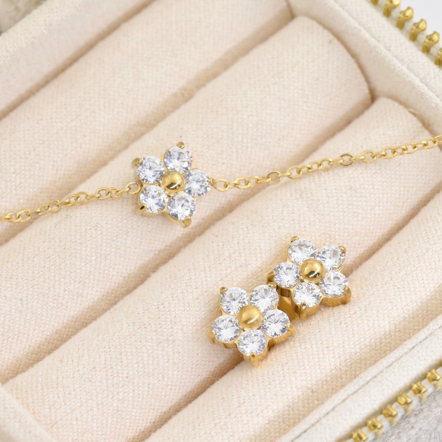 Gold cz flower bracelet abd two stud earrings on a beige jewelry box