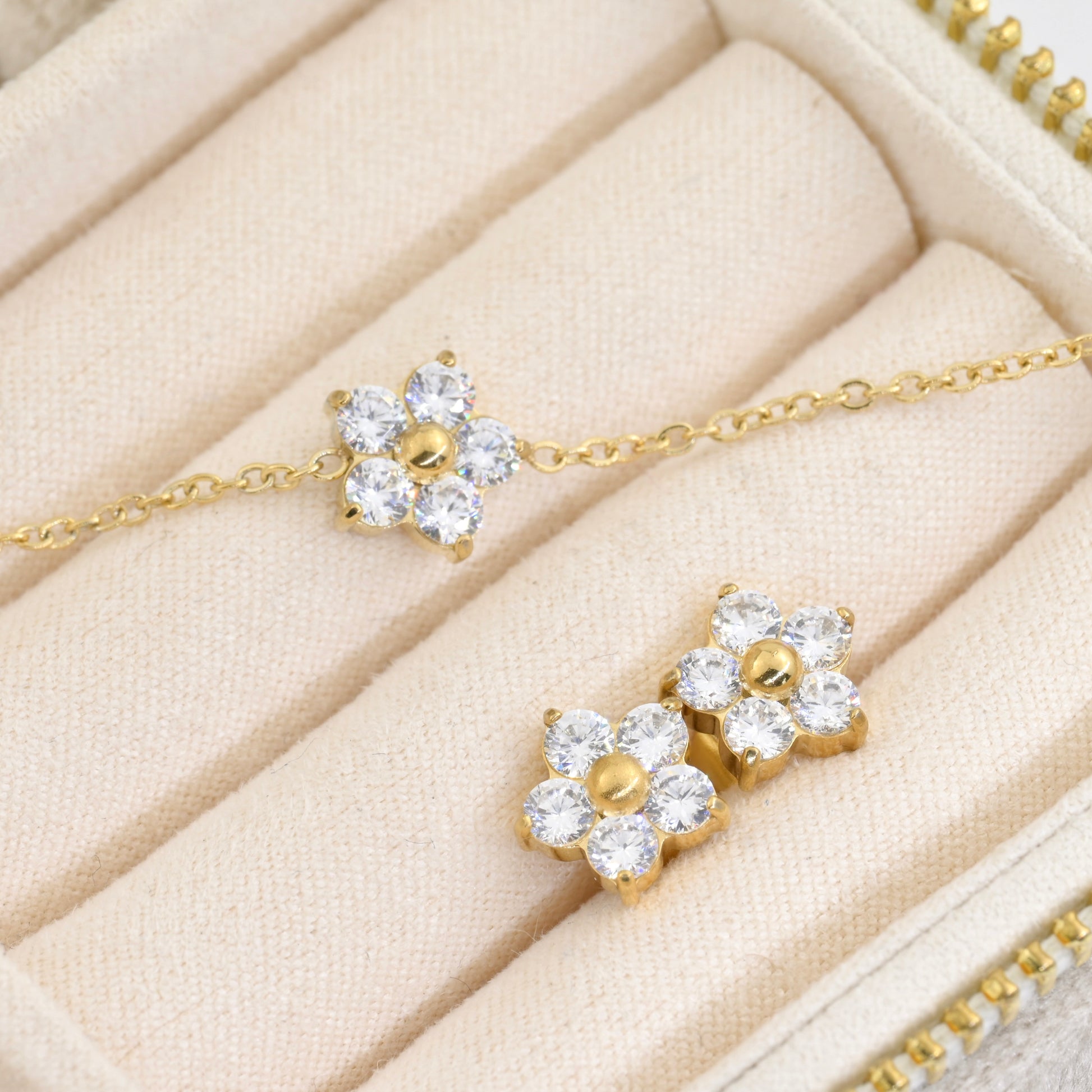 Gold cz flower bracelet abd two stud earrings on a beige jewelry box