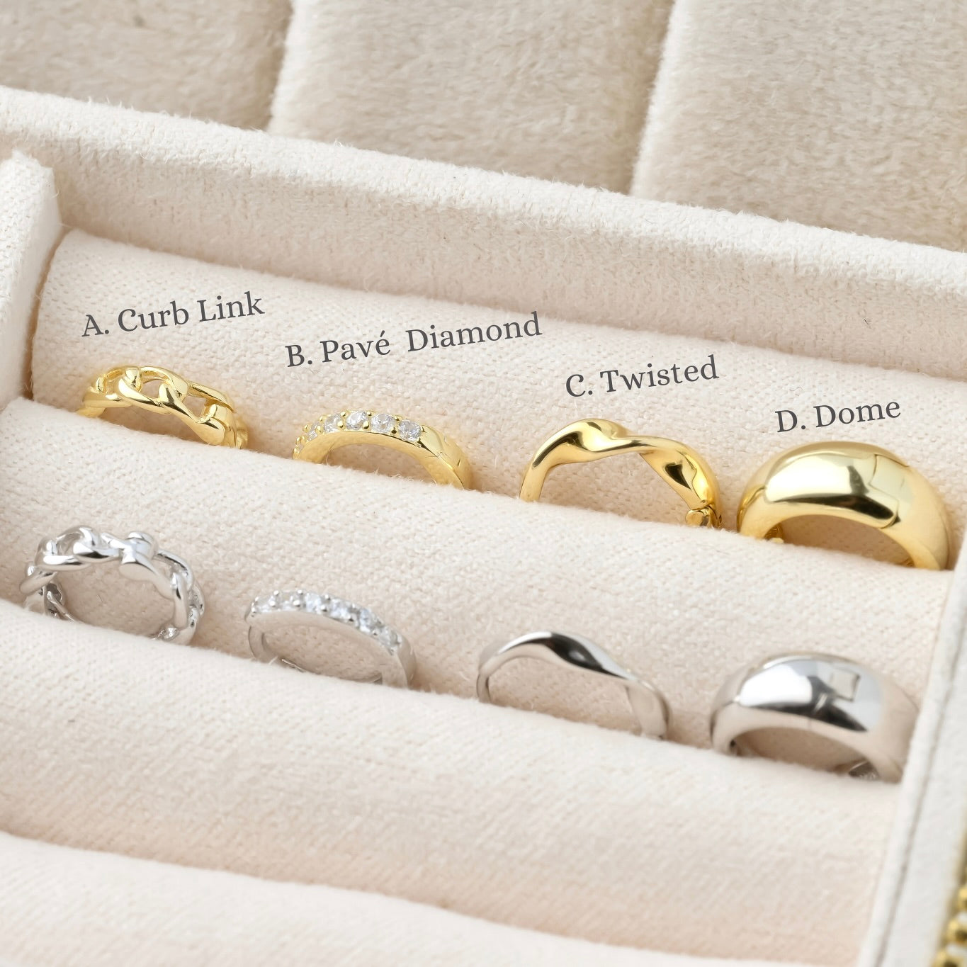 Set of gold and silver earrings displayed with design labels in a jewelry box with labels.