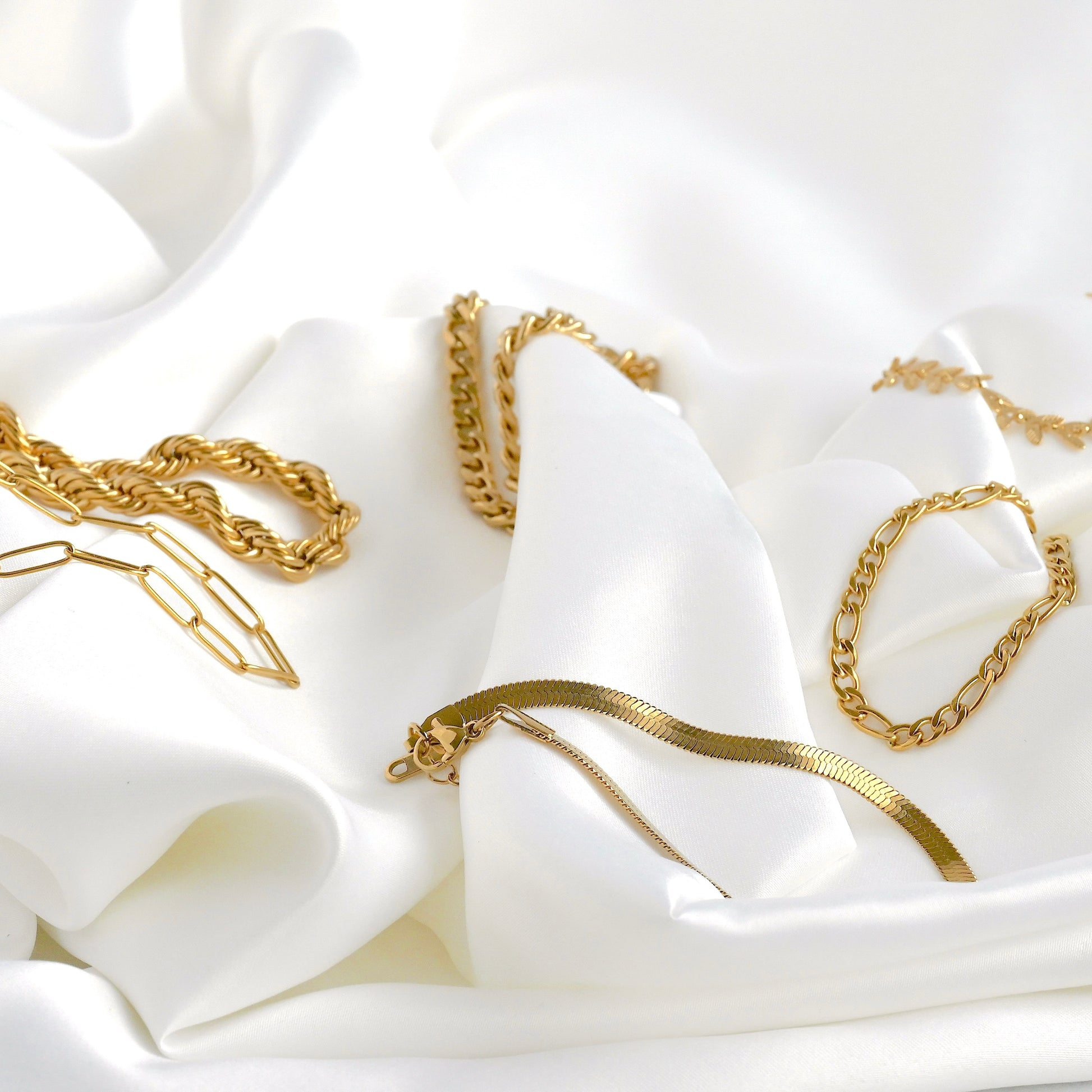 Gold chain bracelets on a white fabric background